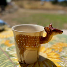 Deer-shaped mug on a table with a blurred outdoor background