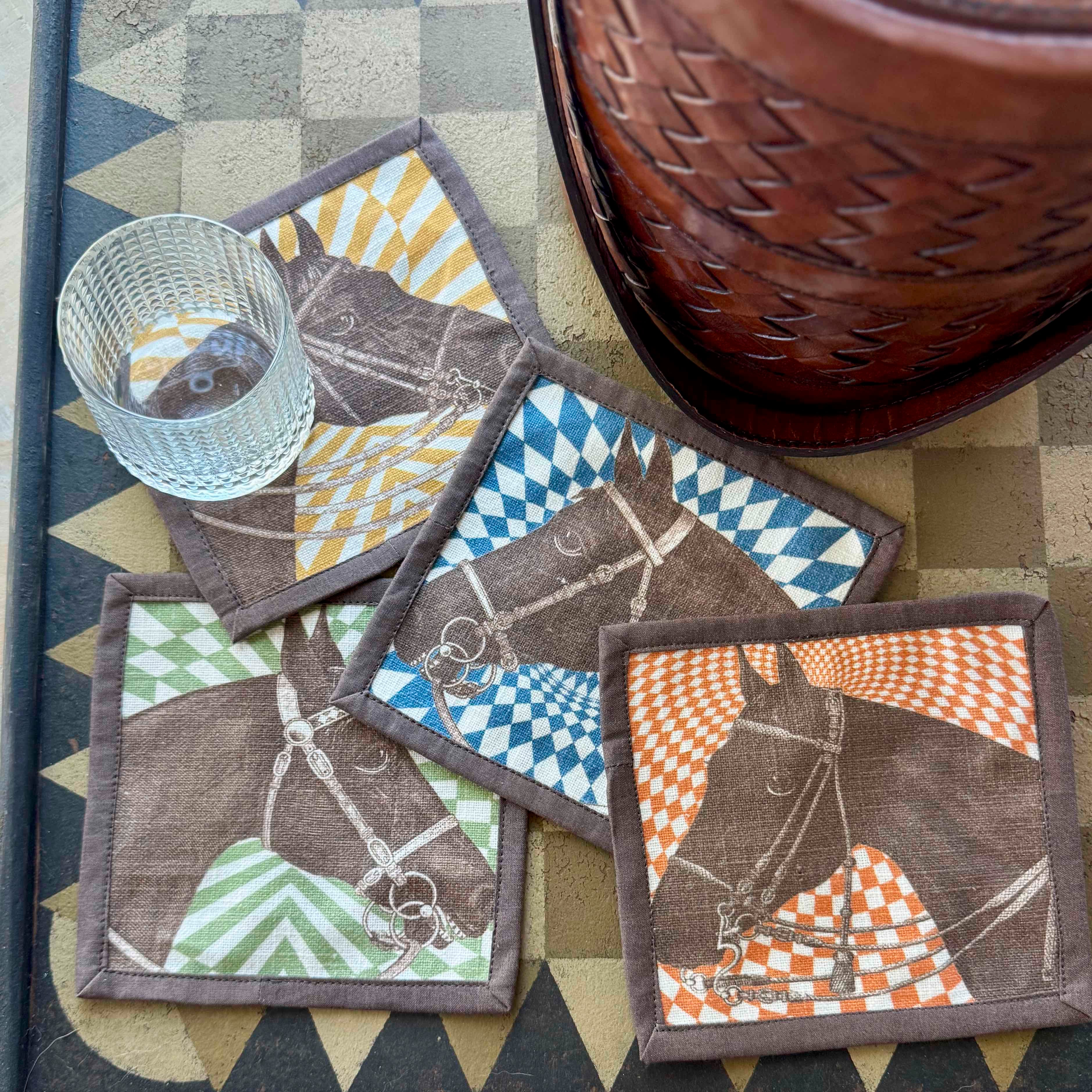 Set of fabric coasters with horse designs on a checkered surface.