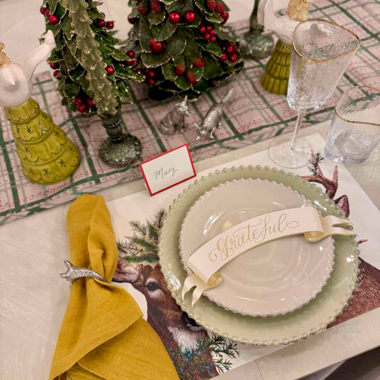 Christmas-themed table setting with plates, napkin, and decorative elements on a patterned tablecloth.