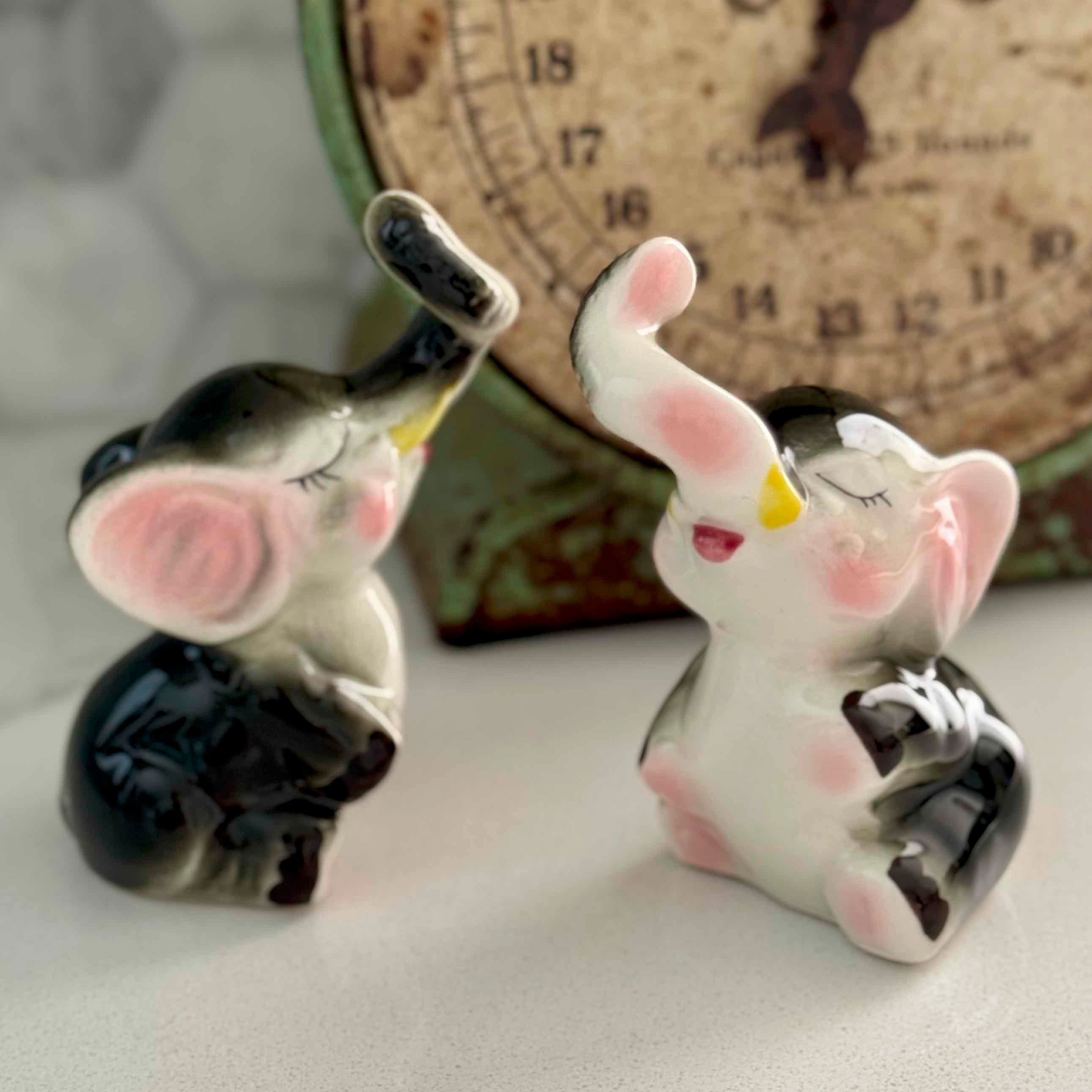 Two ceramic elephant figurines with a vintage clock in the background