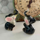 Two ceramic elephant figurines in front of an old-fashioned scale.