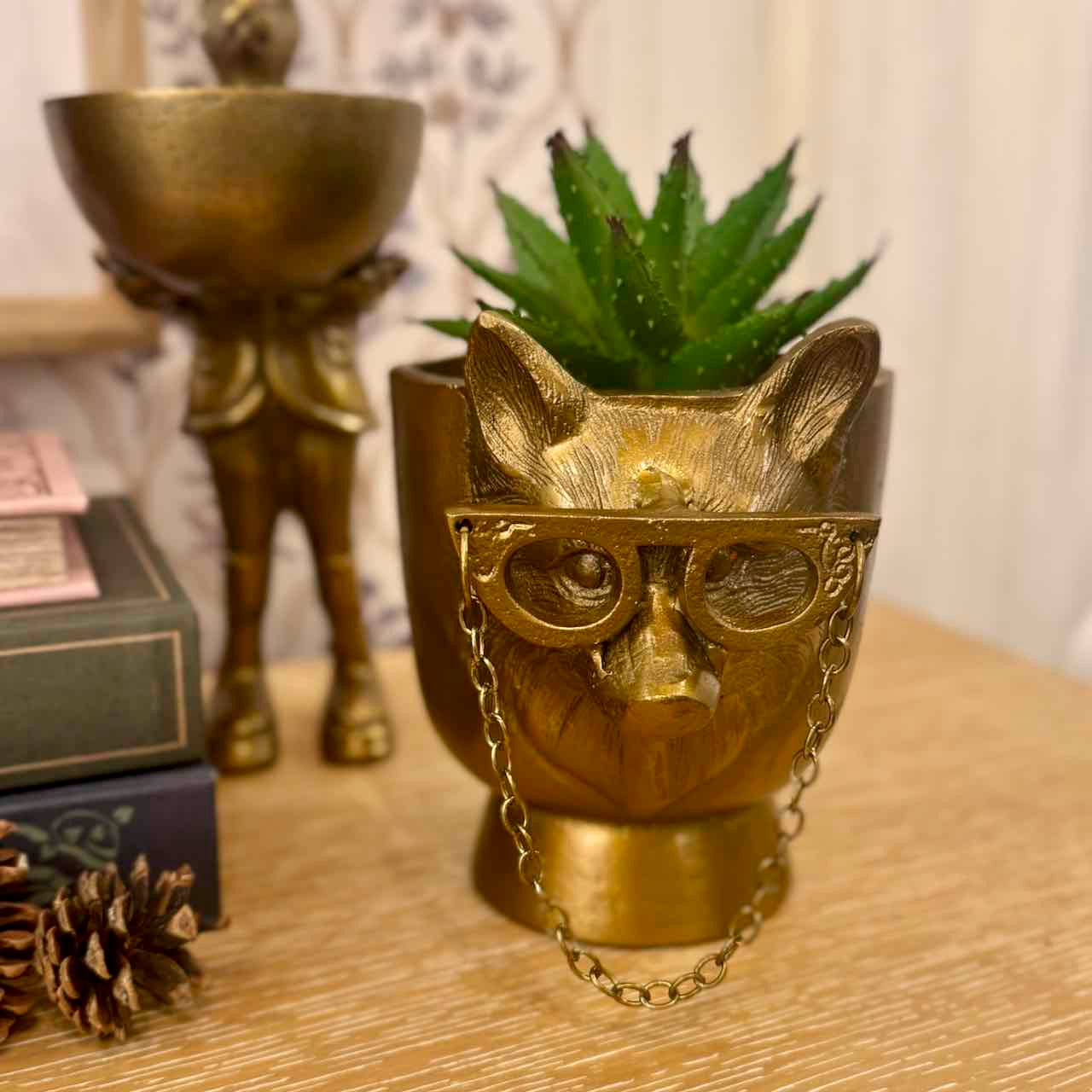 Gold cat-shaped planter with glasses on a wooden surface
