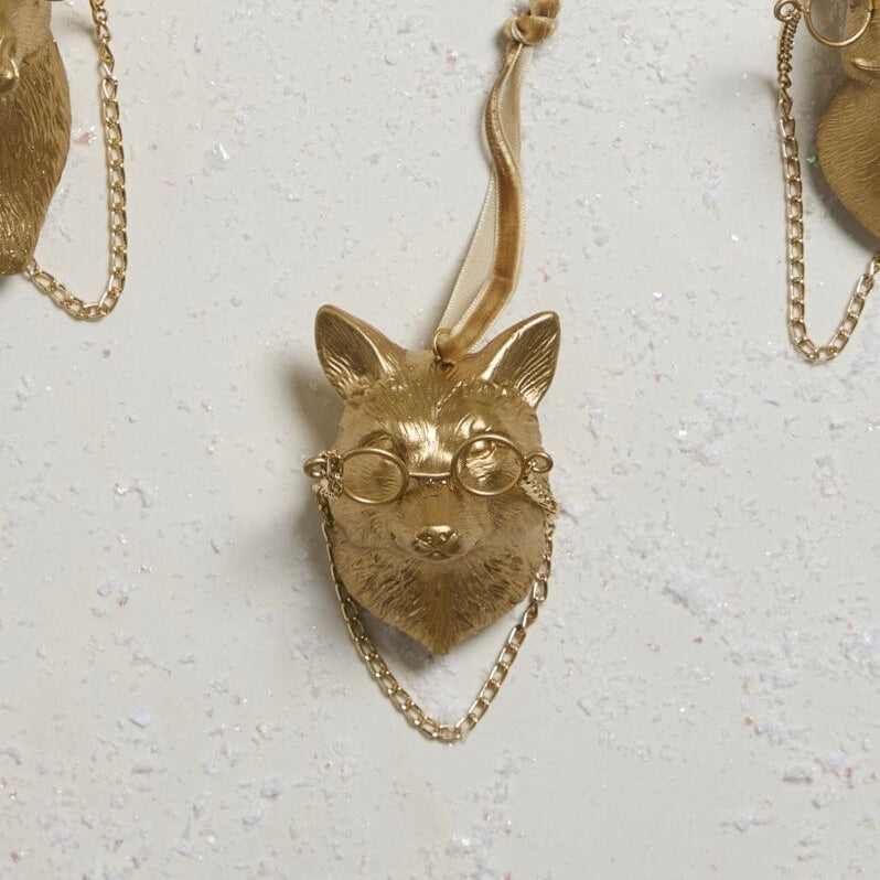 Gold fox pendant with glasses on a light gray background