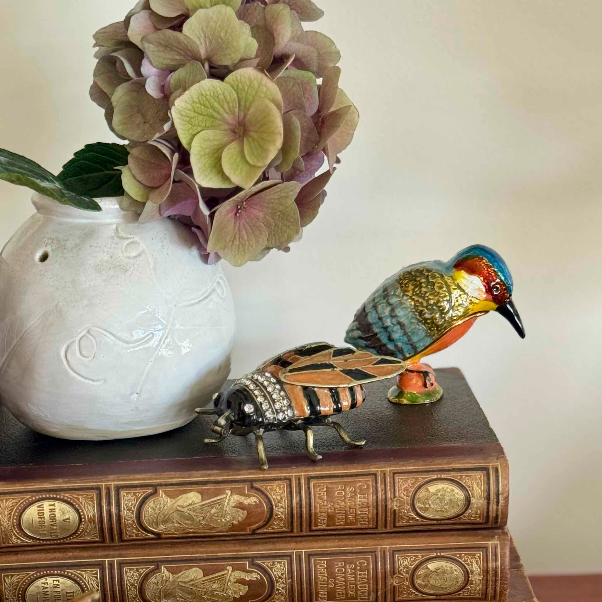 Decorative items including a ceramic vase with flowers, a beetle figurine, and a bird figurine on a book.