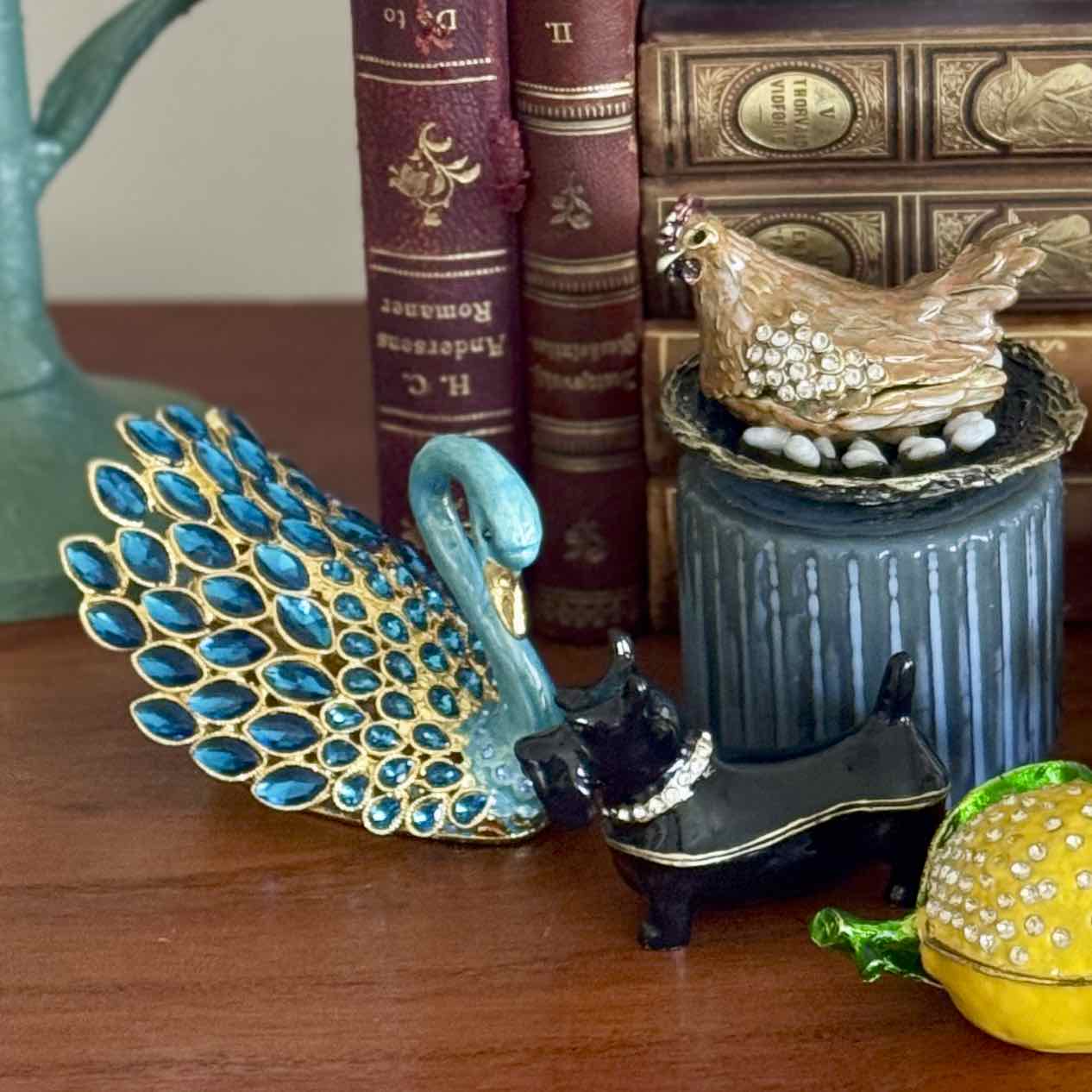 Decorative peacock figurine with other small objects on a wooden surface.