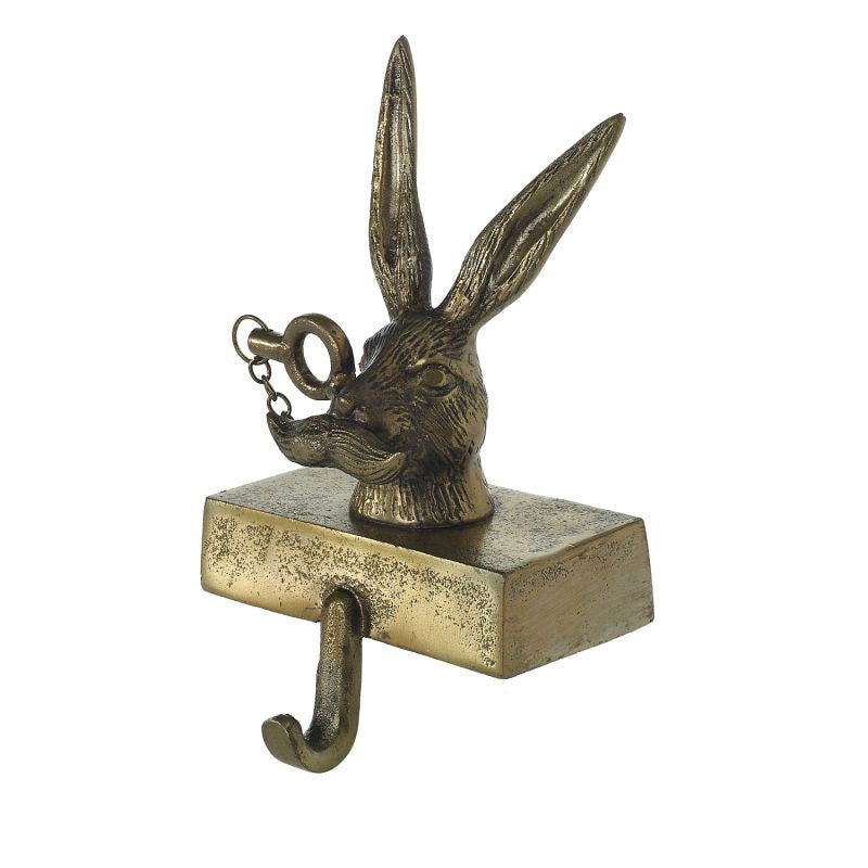 A metal stocking holder in the shape of a rabbit, with a hook for hanging and an antique gold finish.