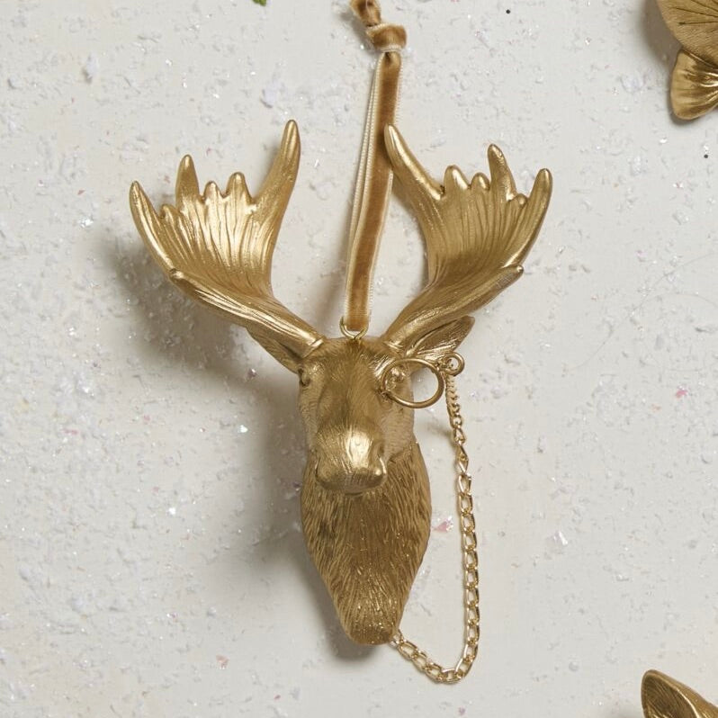 Gold deer head necklace on a textured white background