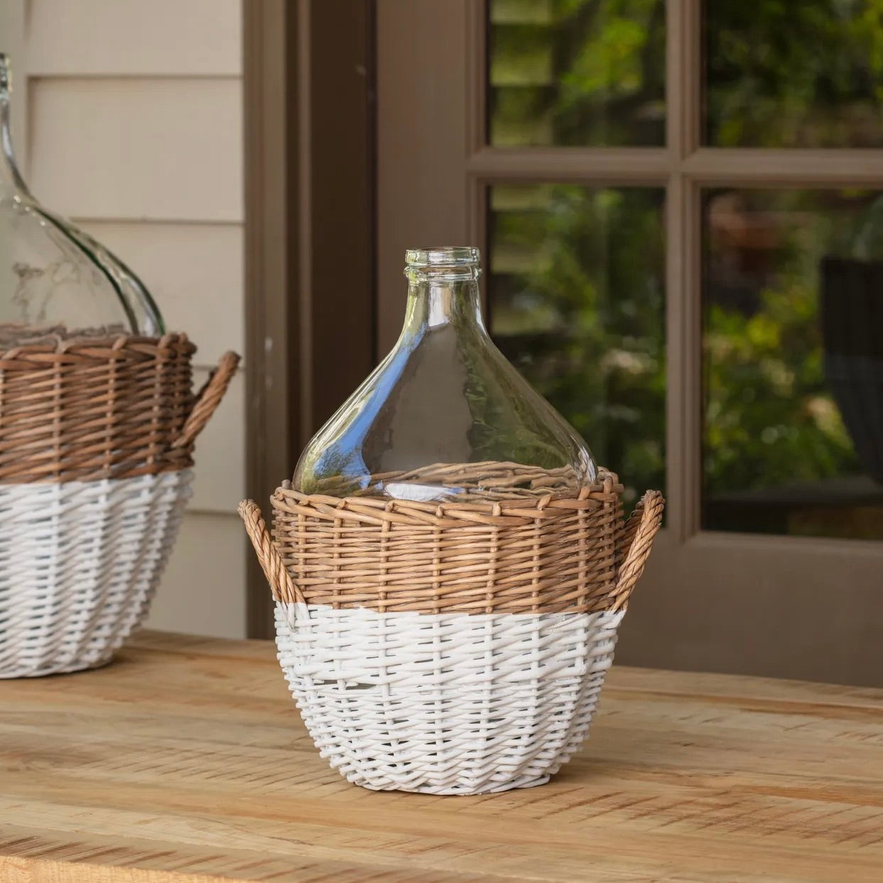 Wicker basket with a glass bottle on a wooden surface outdoors