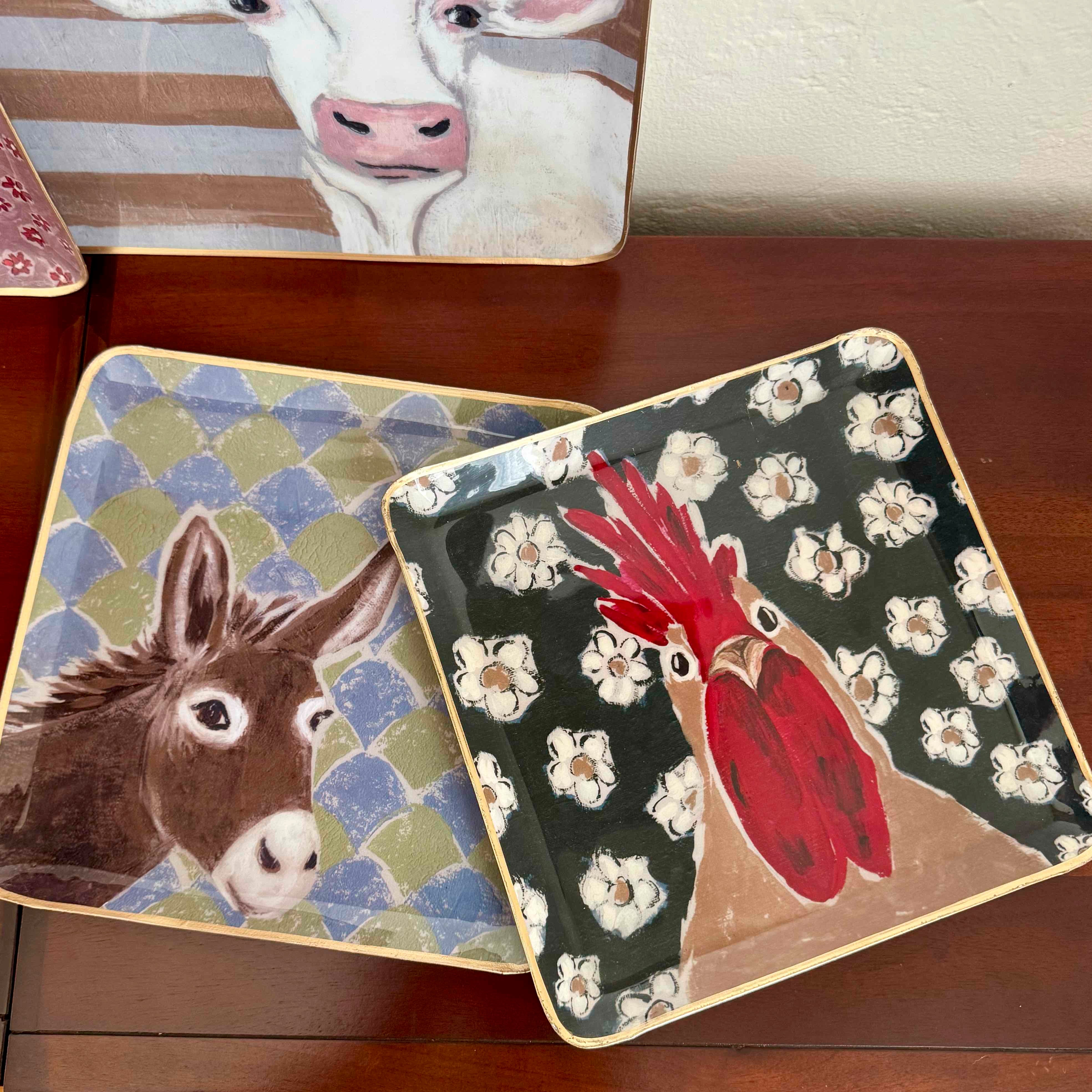 Set of decorative trays with animal illustrations on a wooden surface
