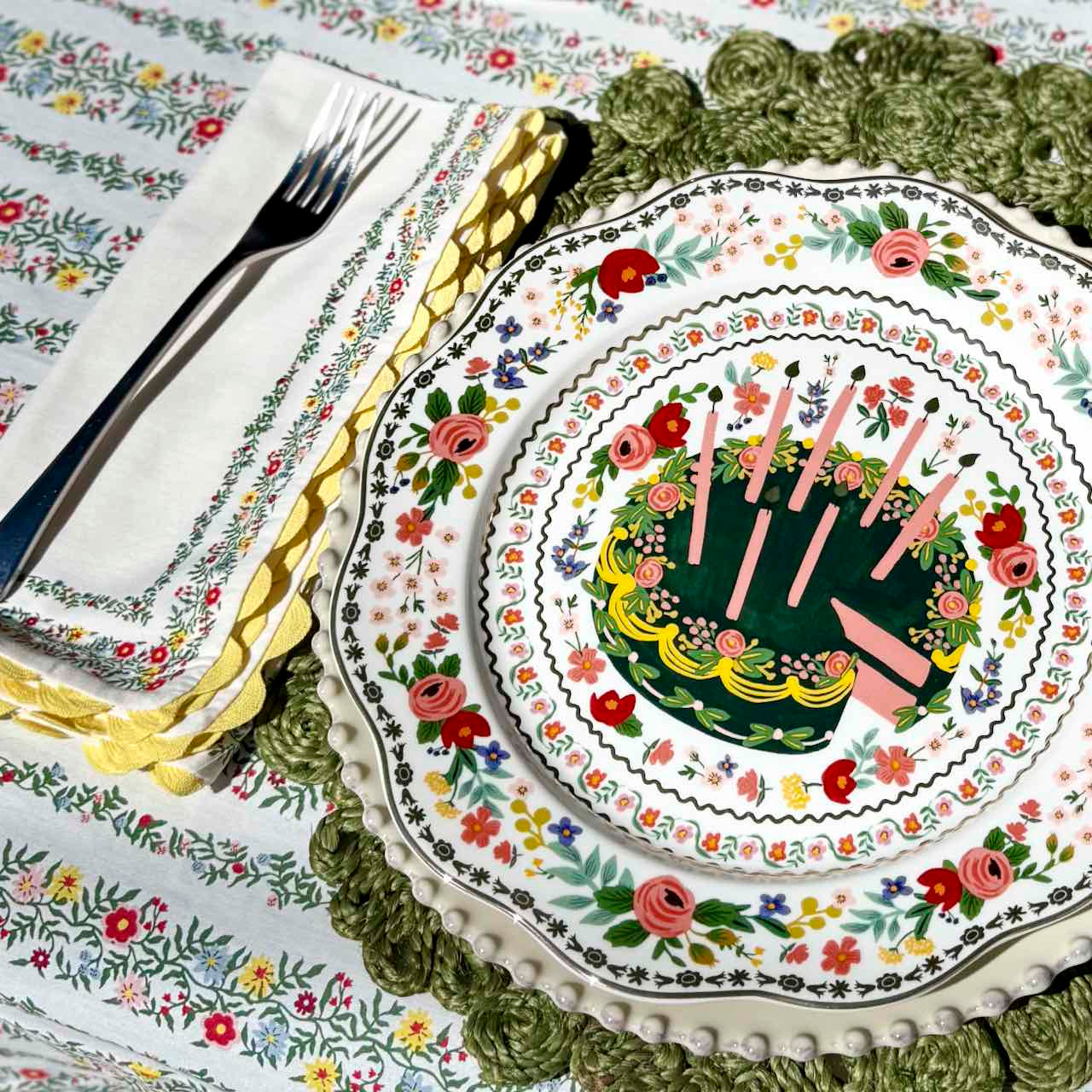Decorative plate with floral and candle design on a matching tablecloth.