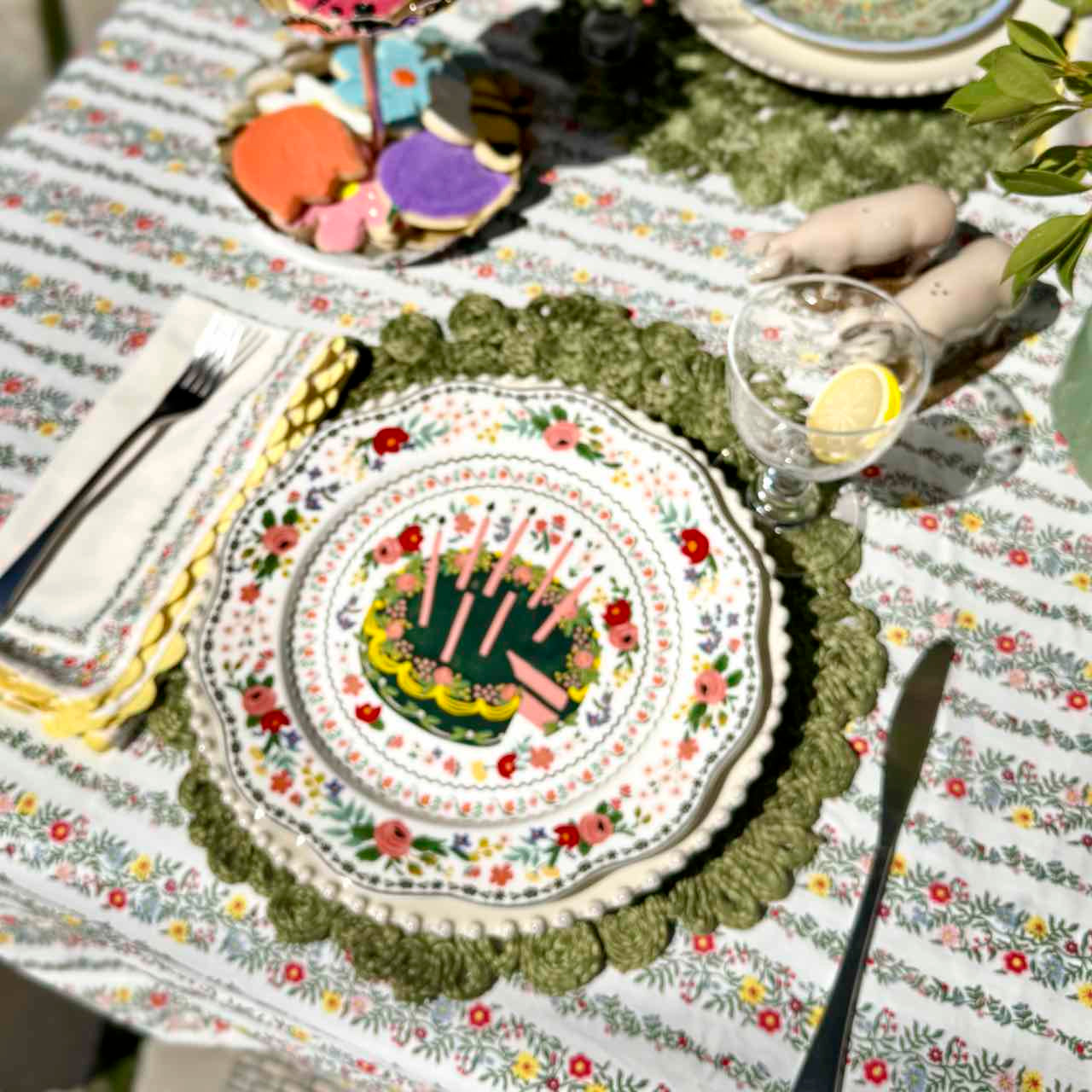 Decorative table setting with a floral tablecloth, colorful plates, and cutlery.