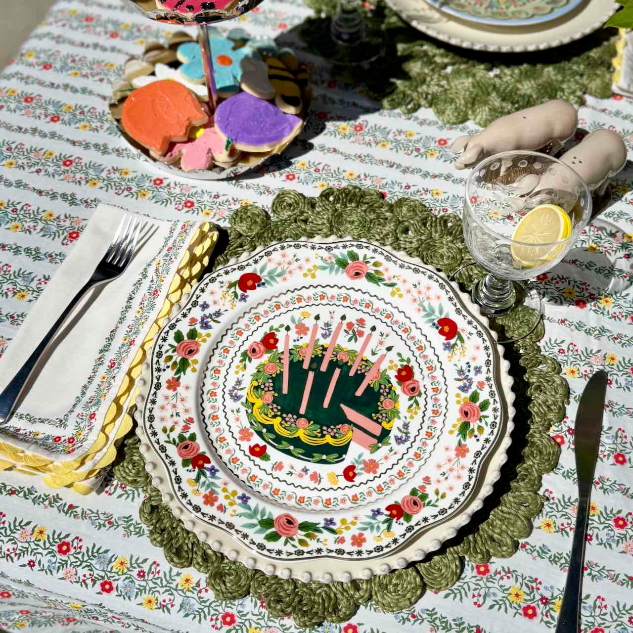 Decorative table setting with a floral tablecloth and a plate with a cake design.
