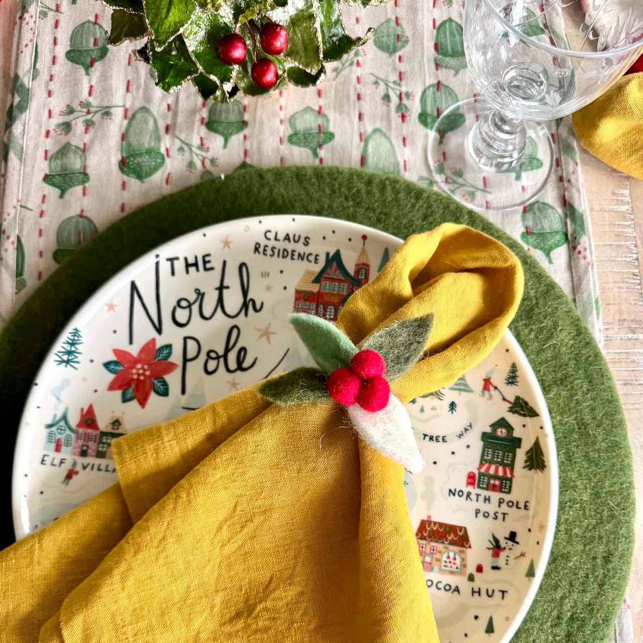 Christmas-themed place setting with 'The North Pole' plate and yellow napkin.