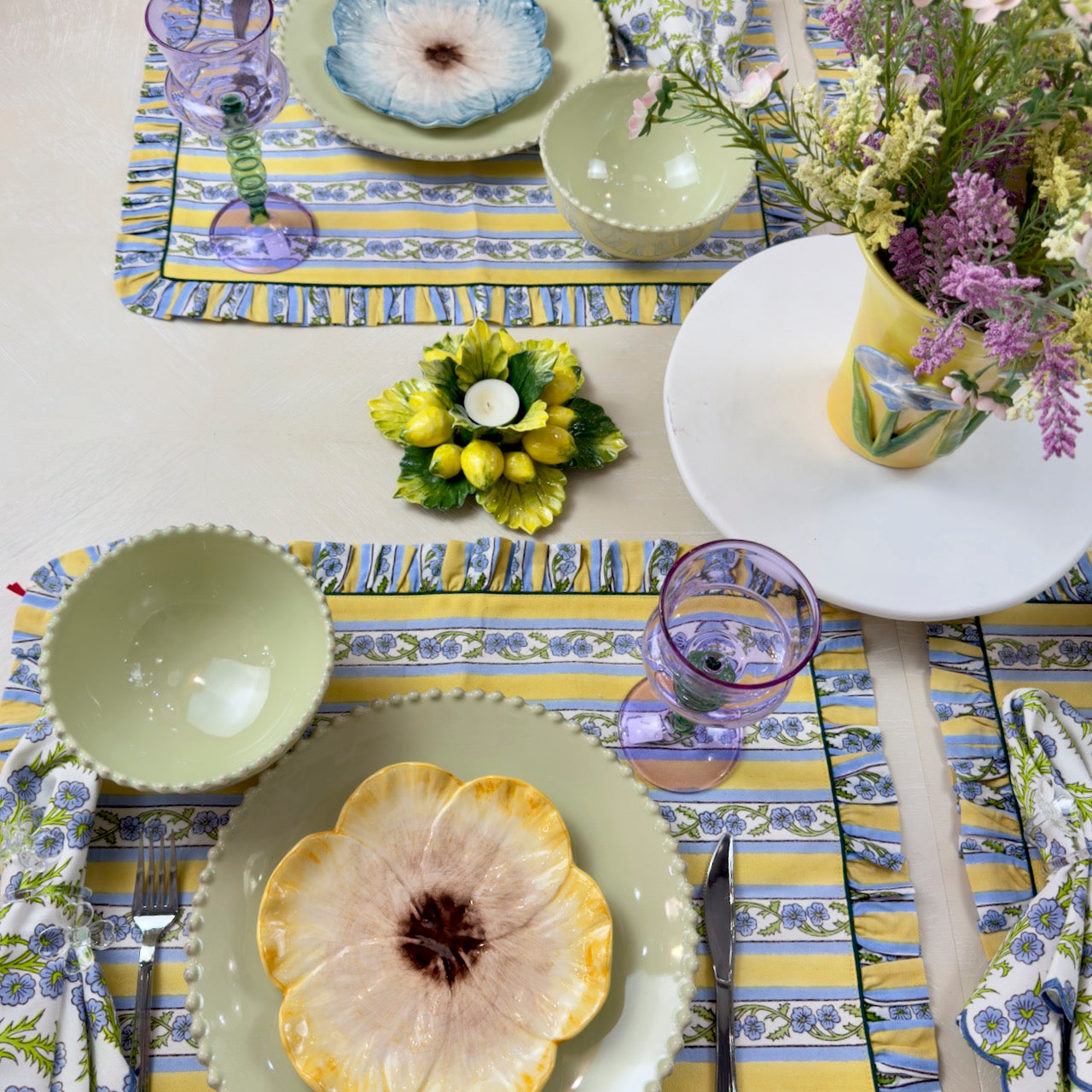 Decorative table setting with floral plates, glasses, and a colorful placemat.