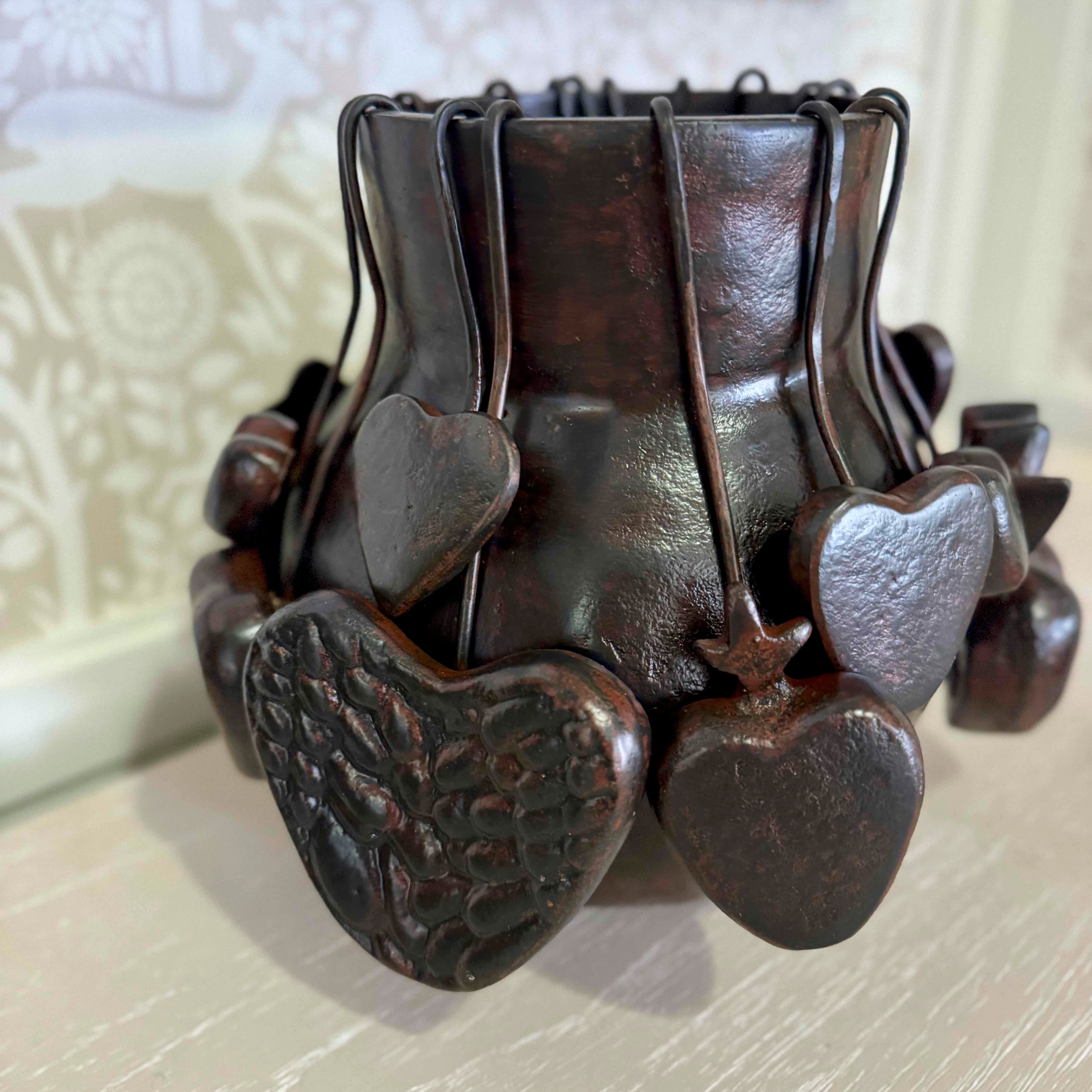 Decorative metal holder with heart designs on a textured surface