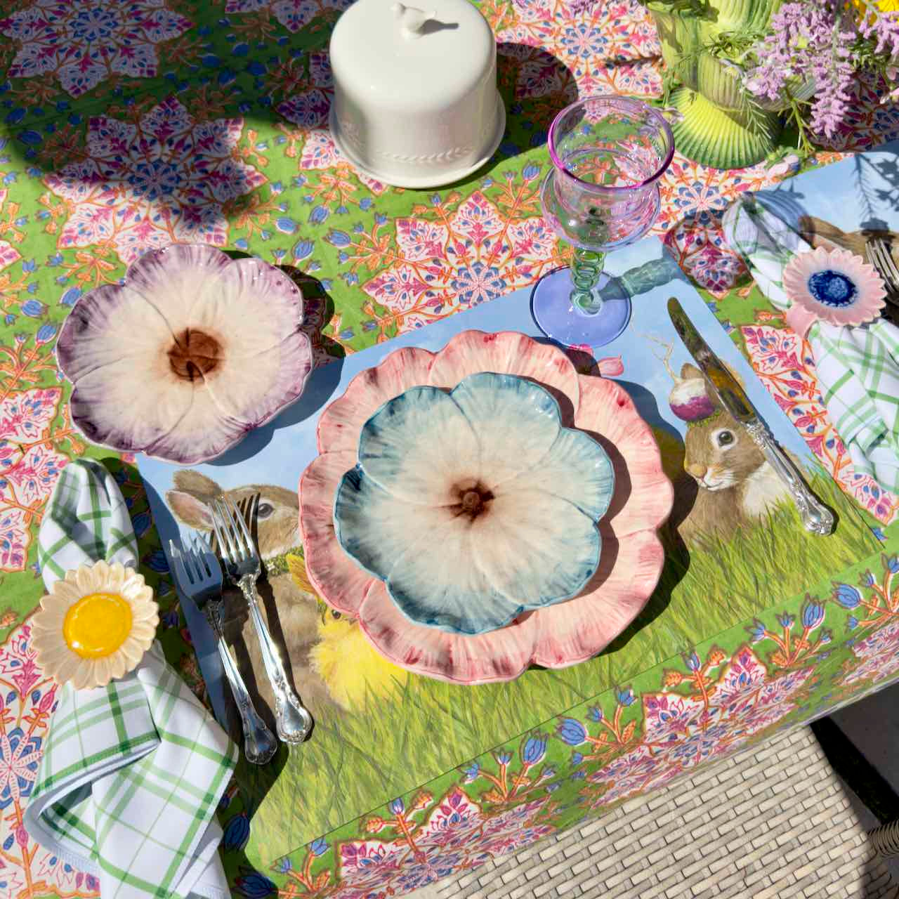 Colorful table setting with floral plates and a patterned tablecloth.