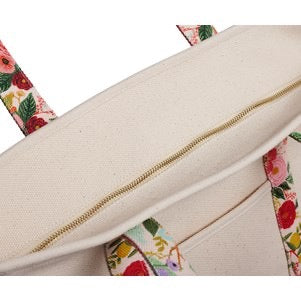 Close-up of a beige cushion with floral-patterned trim on a white background