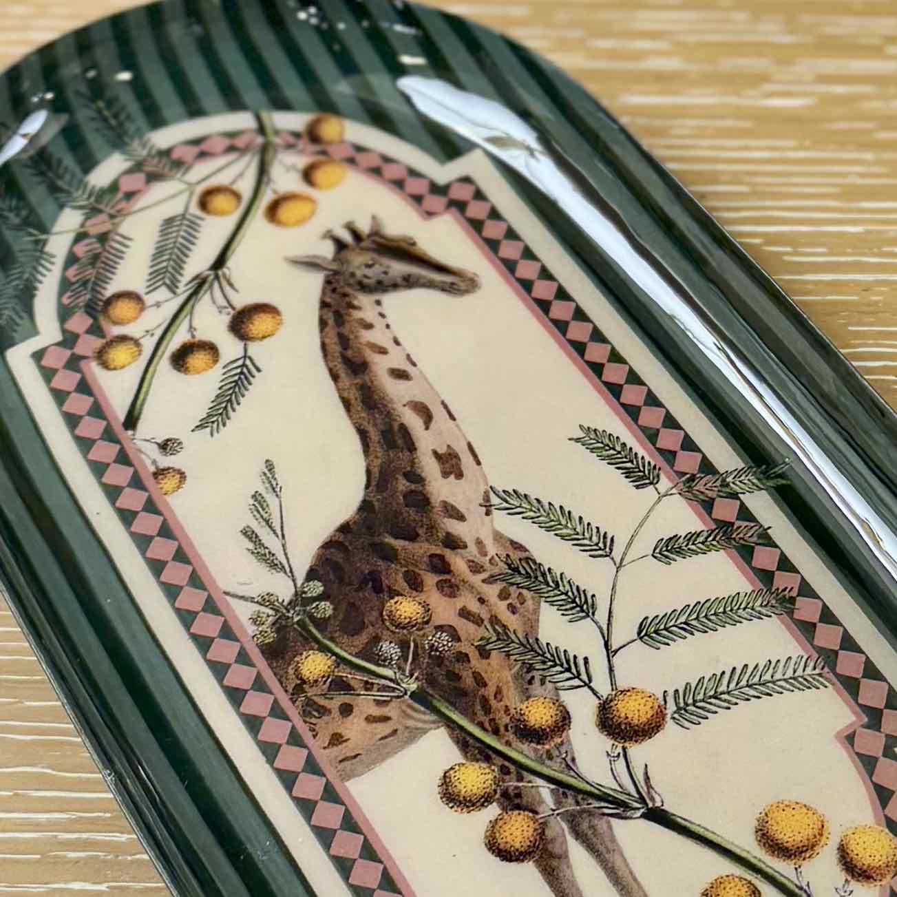 Decorative tray with a giraffe illustration and floral elements on a patterned background.