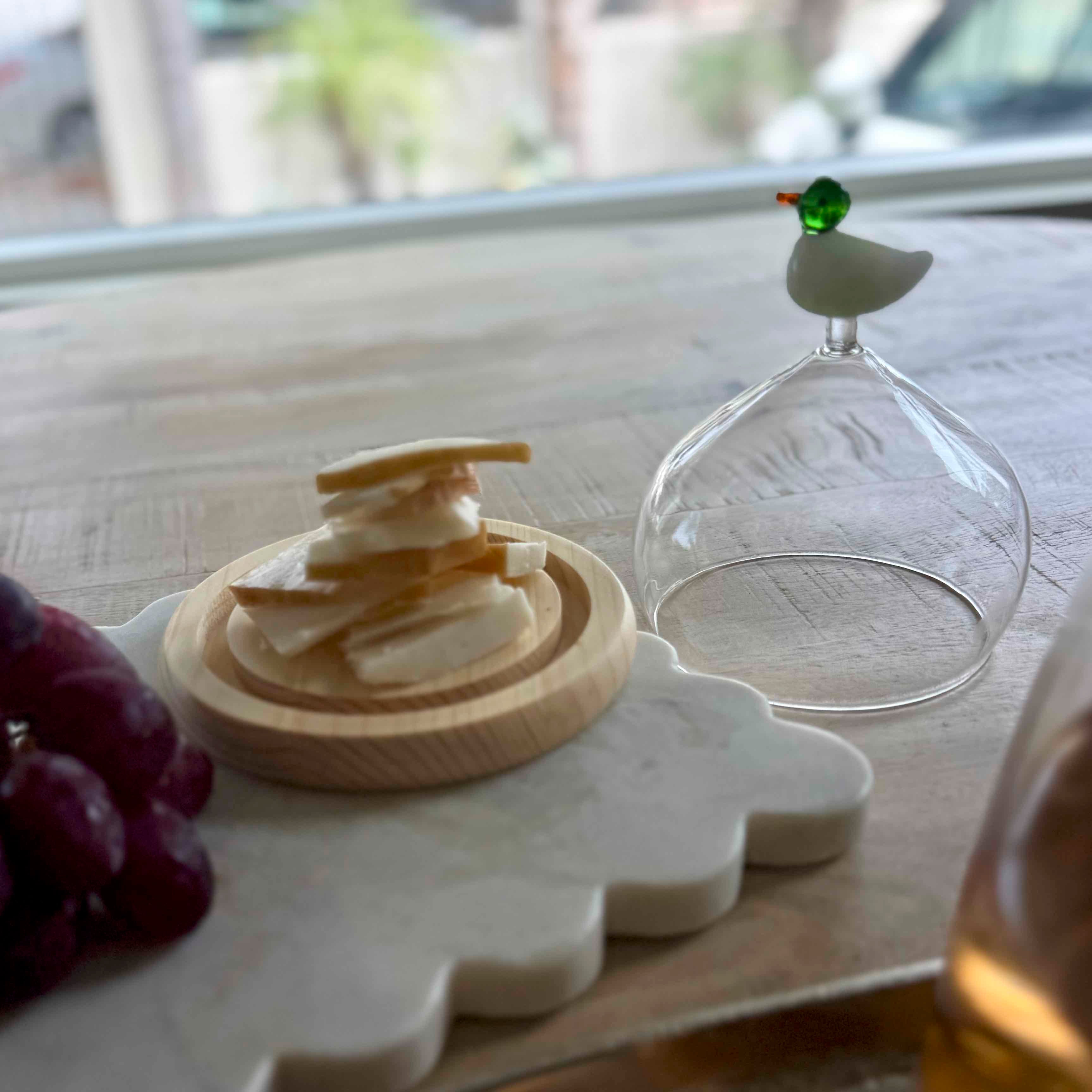 Cheese platter with crackers, grapes, and a glass container on a wooden table.