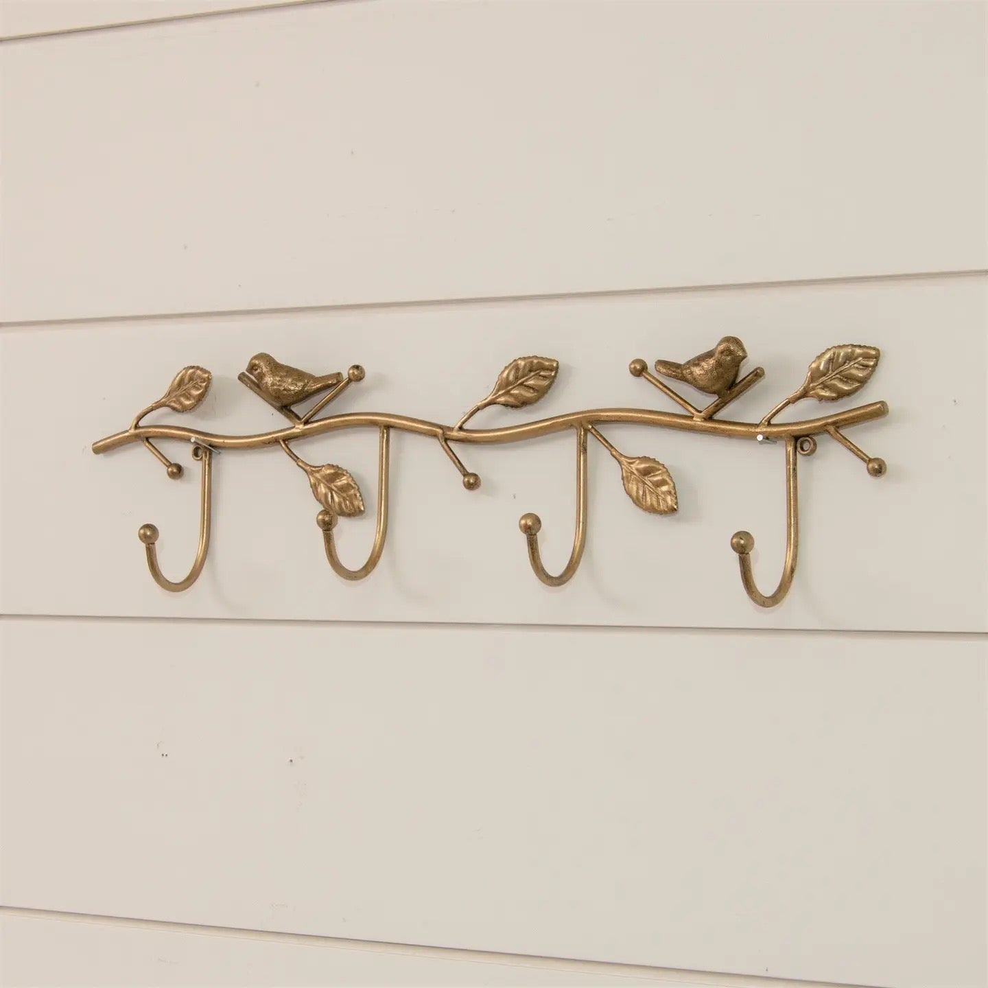 Decorative brass wall hook with birds and leaves on a white background