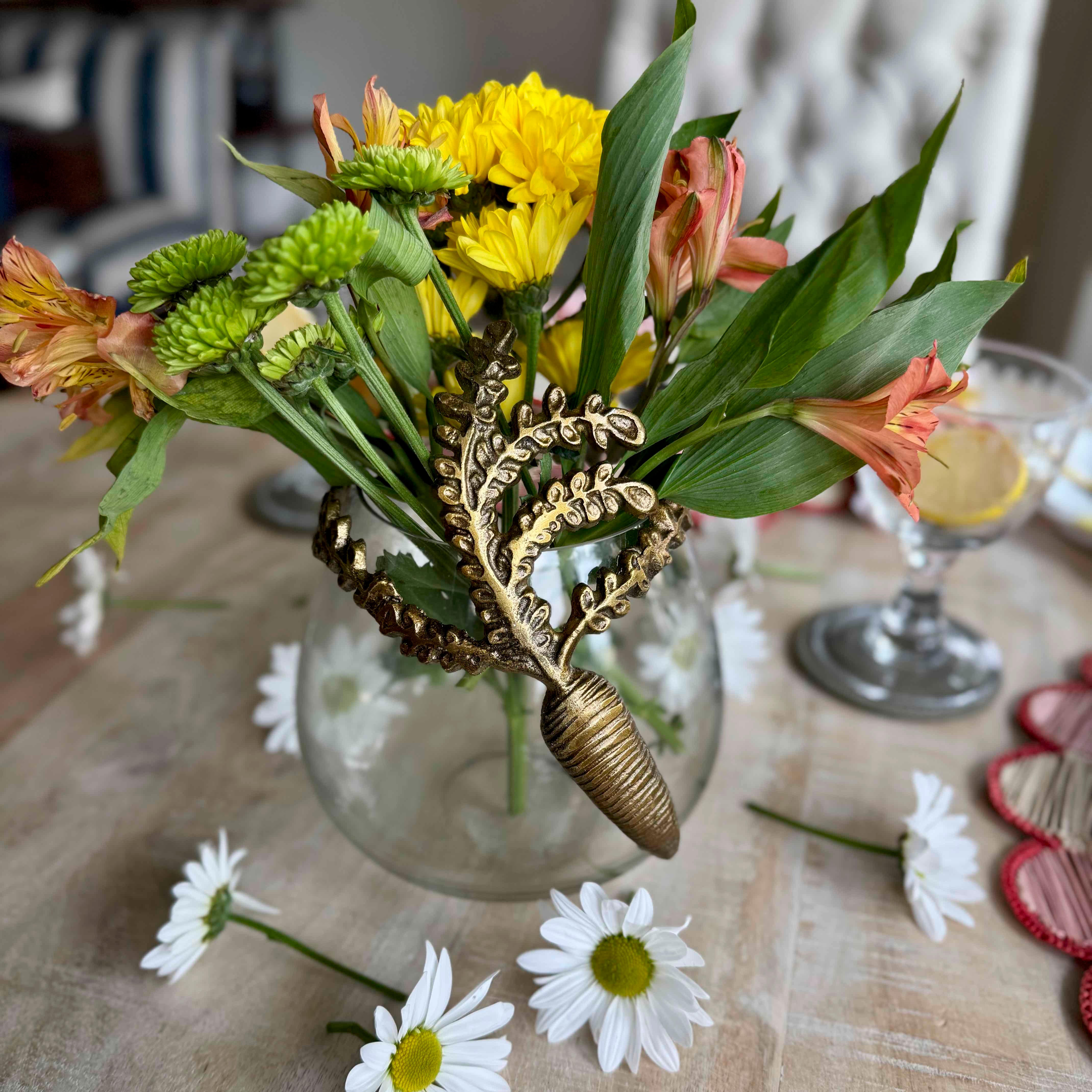 Bouquet of flowers with a decorative shell in a clear vase on a table.