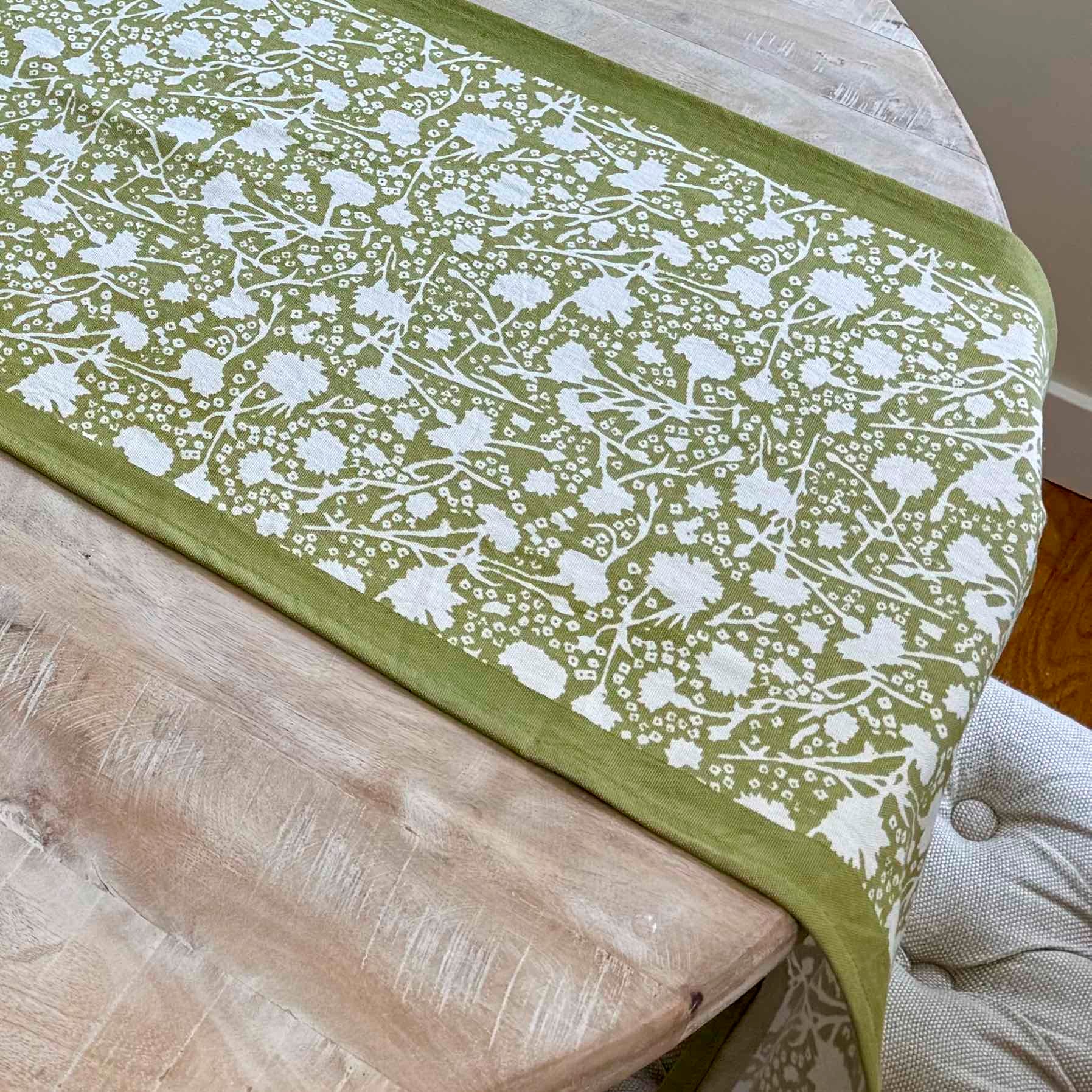 Green and white floral patterned table runner on a wooden table.