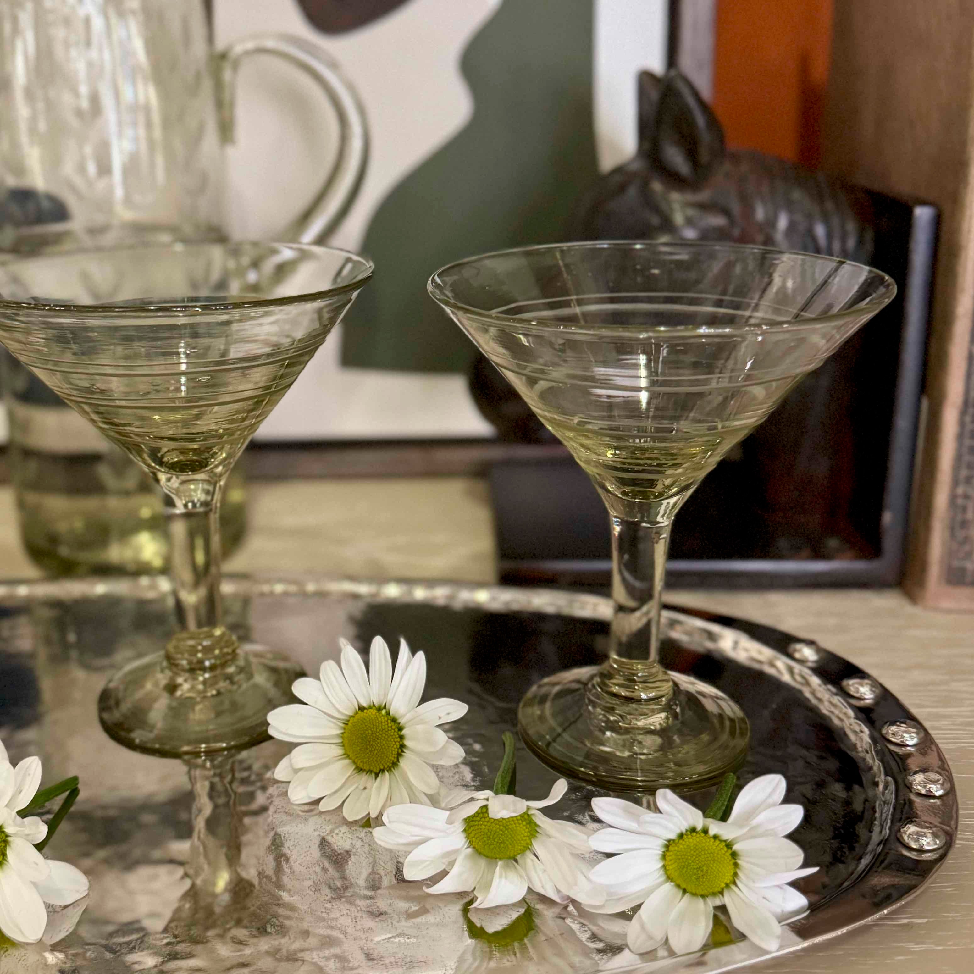 Two martini glasses on a decorative tray with white flowers