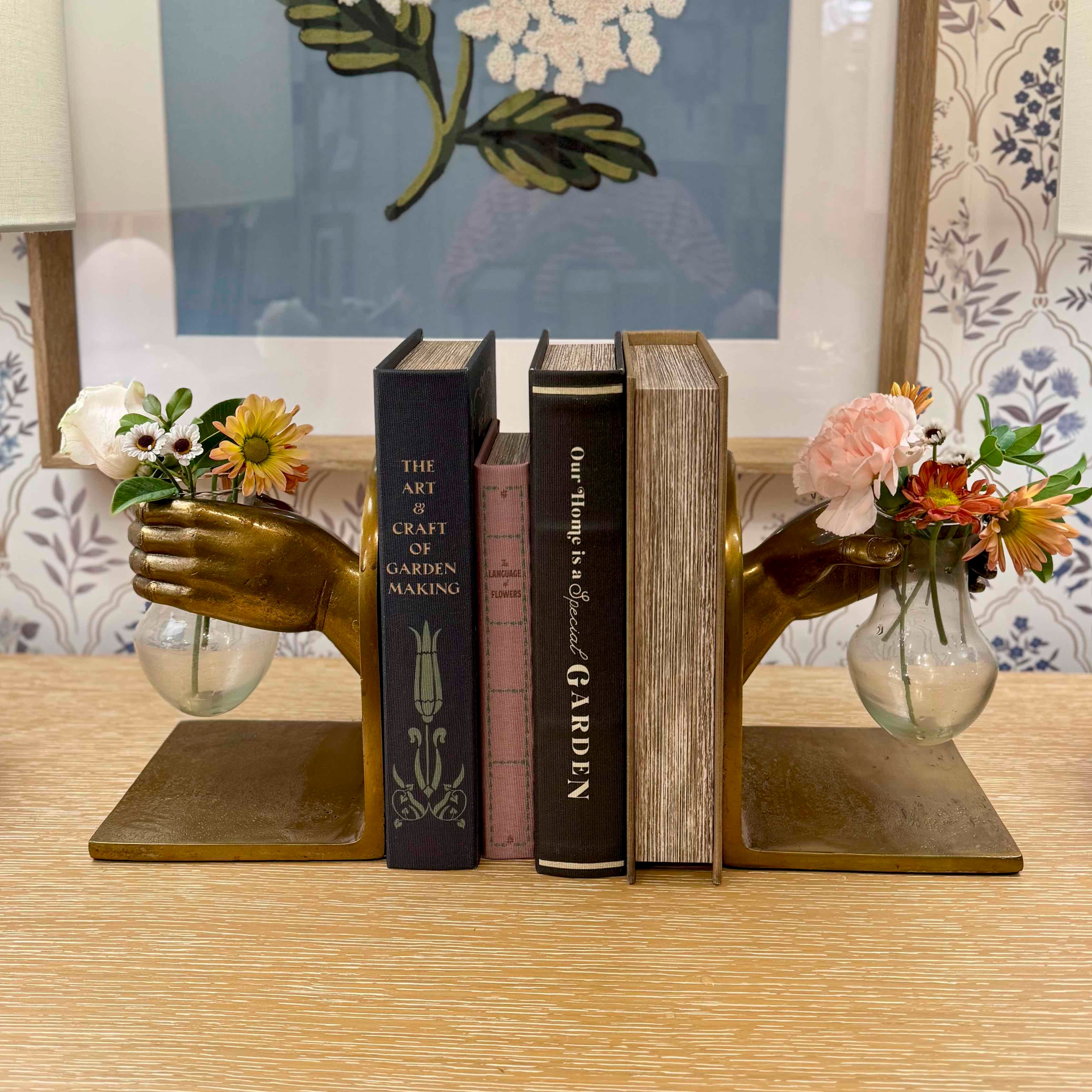 Decorative bookends with floral vases holding flowers on a table.