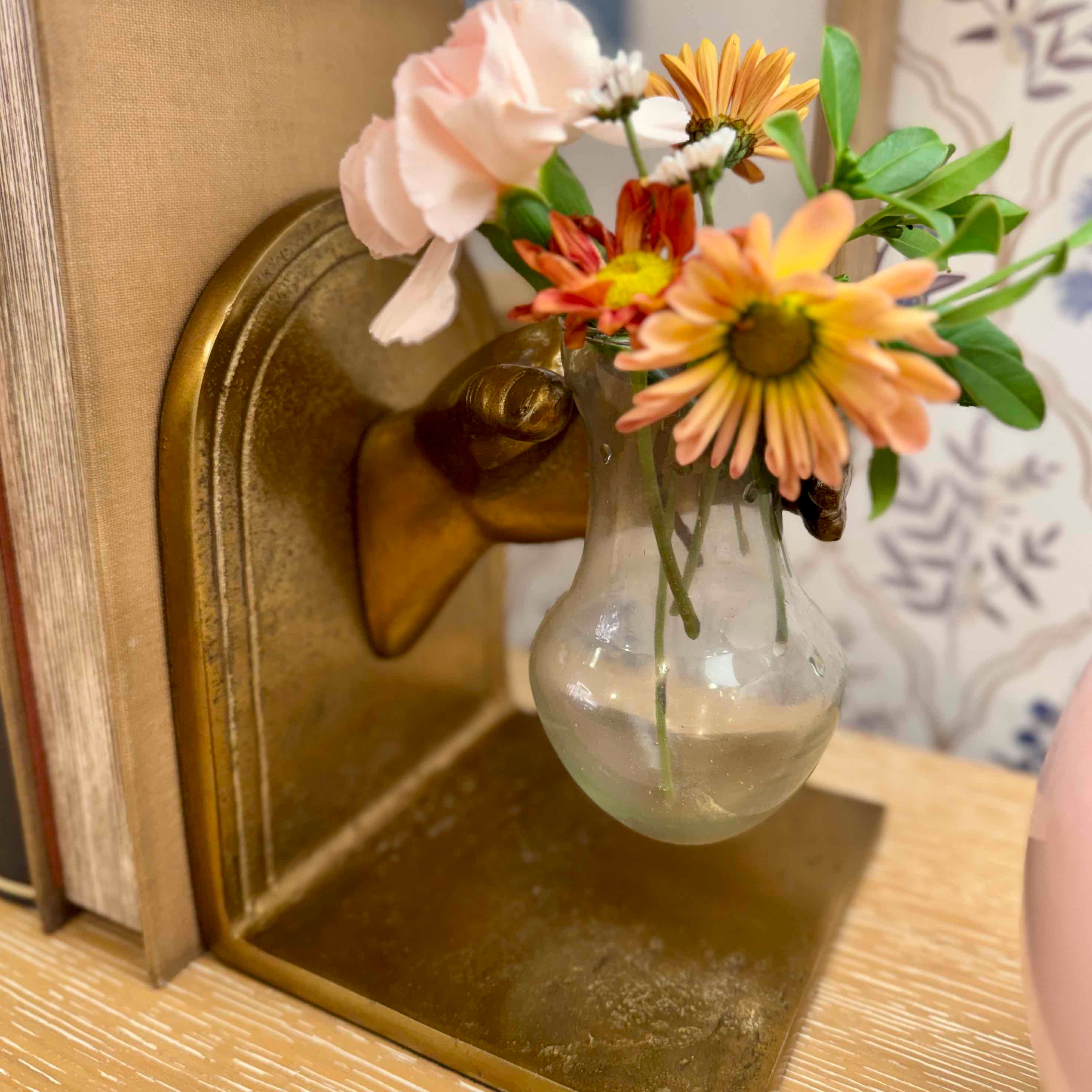 Decorative light bulb vase with flowers attached to a wooden surface