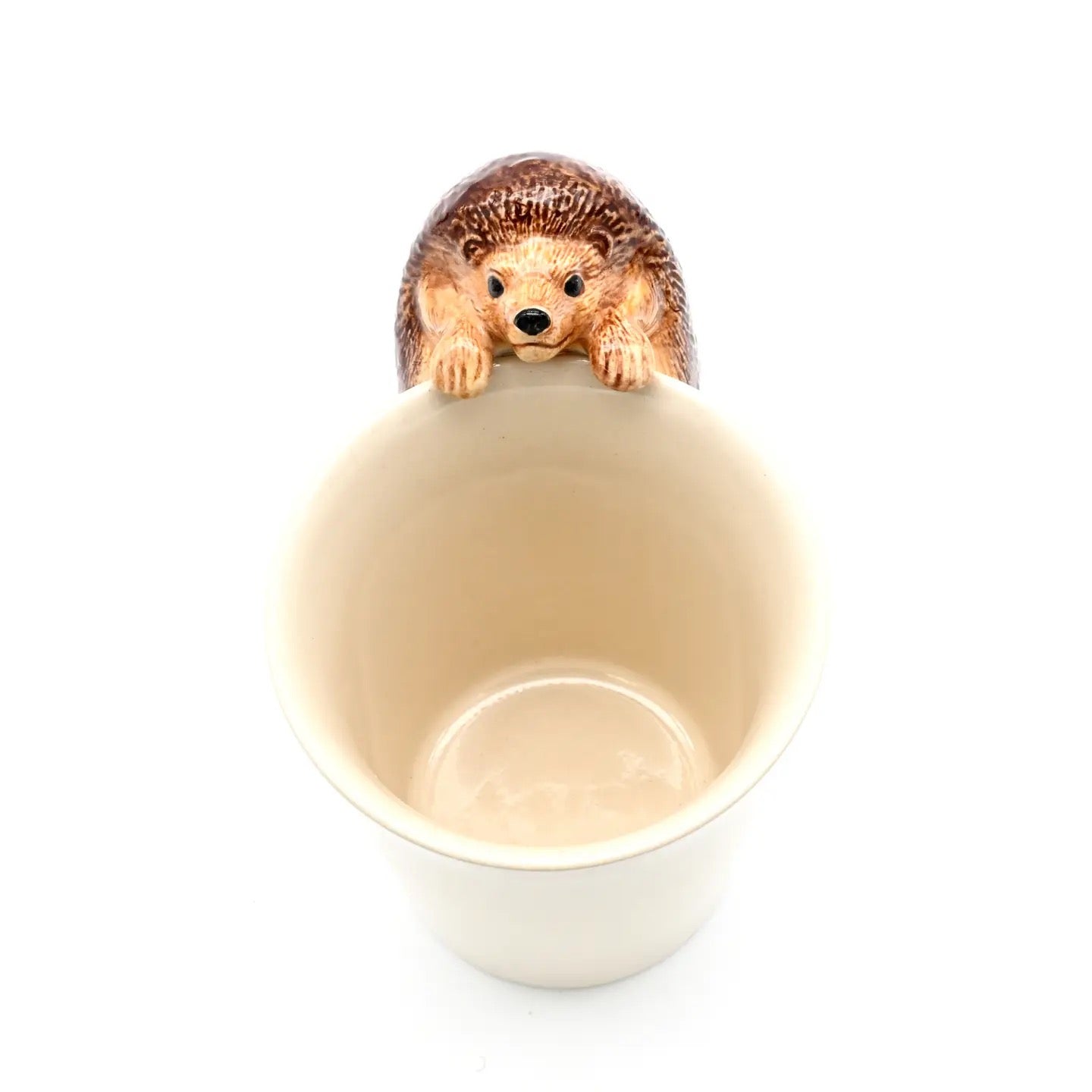 Hedgehog figurine inside a beige ceramic cup on a white background