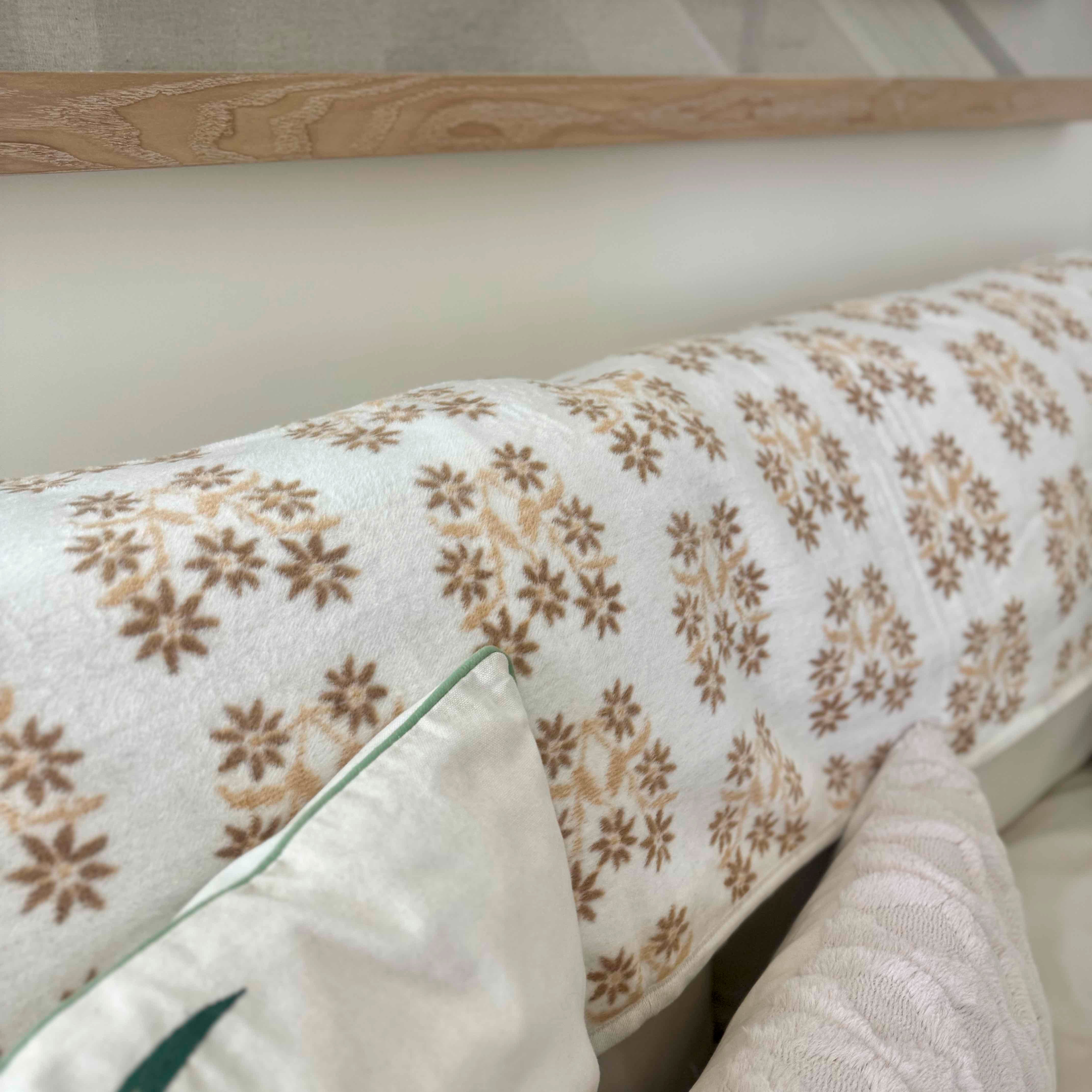 Floral-patterned cushion on a sofa with a wooden headboard in the background