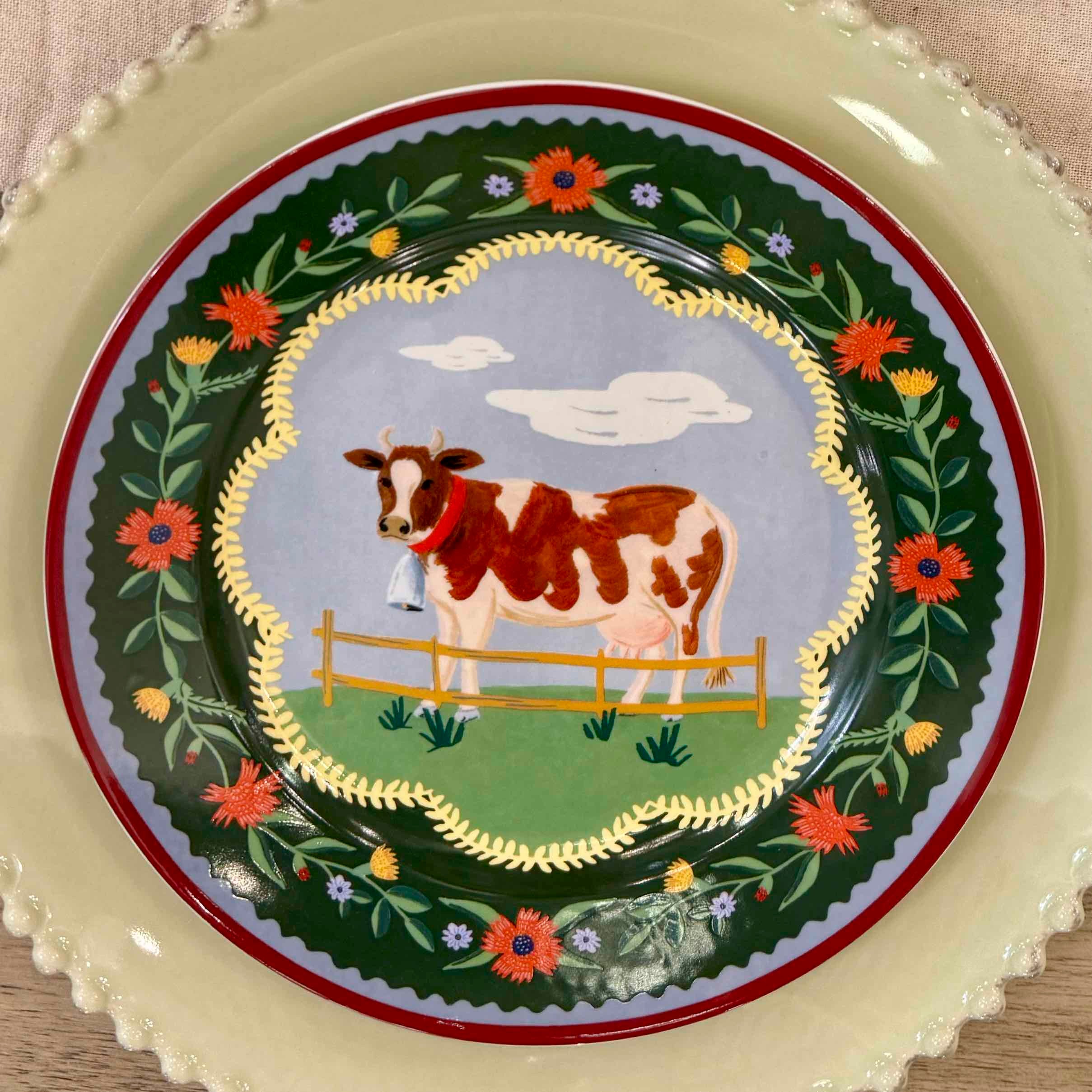 Decorative plate with a cow illustration and floral design on a beige background