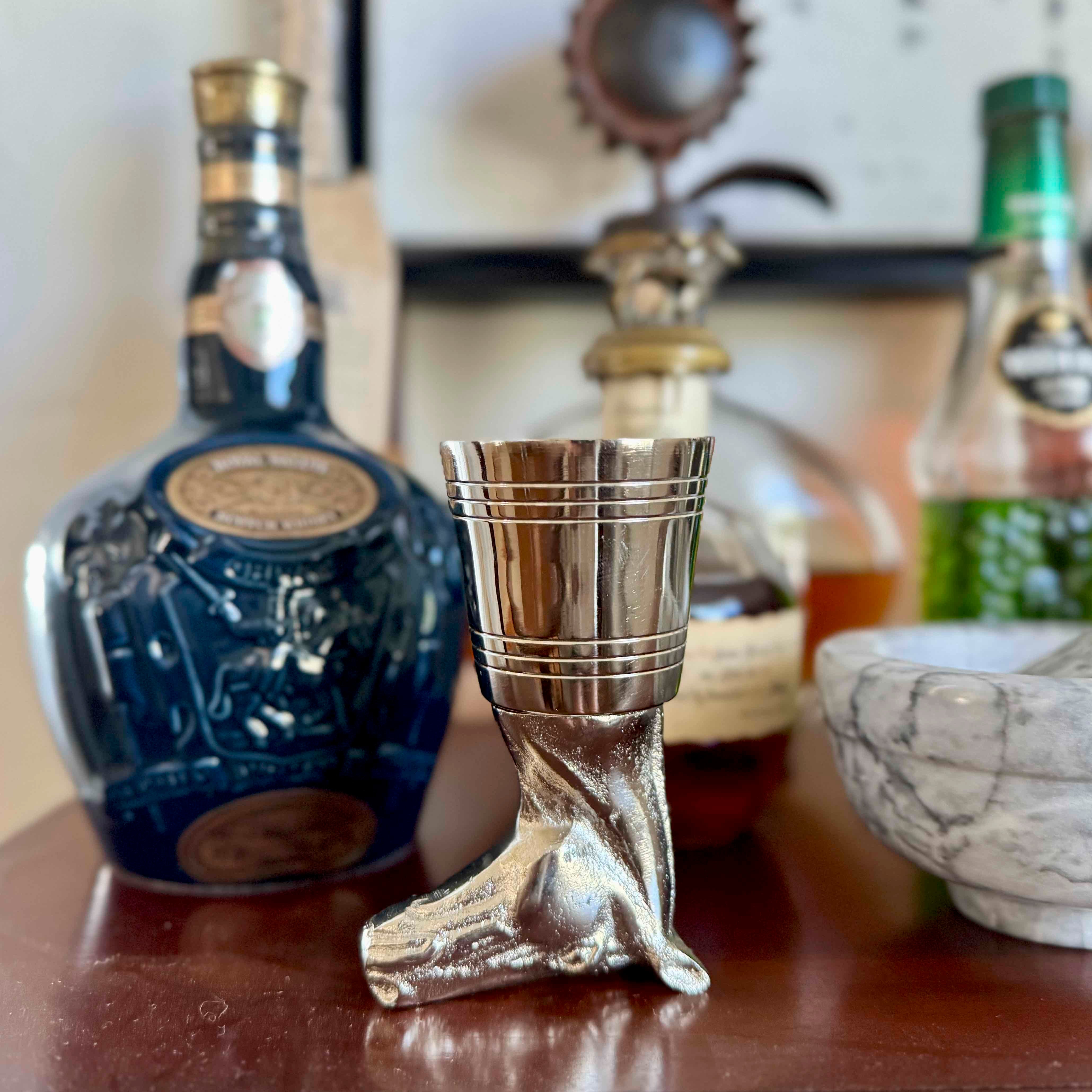 Silver boot-shaped shot glass in front of a bottle of Johnnie Walker Blue Label whisky.