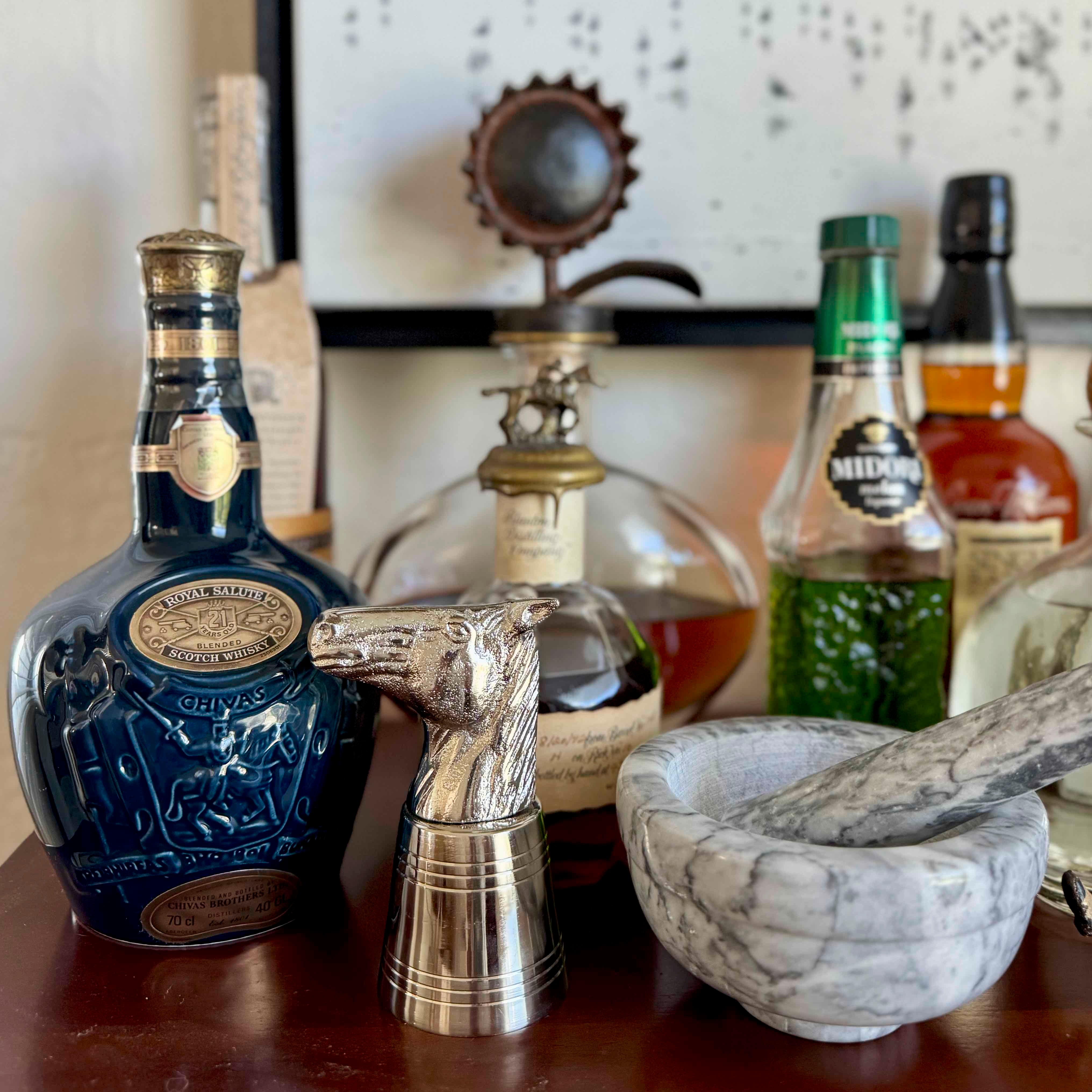 Bottle of Johnnie Walker Blue Label whisky with a silver decanter, marble bowl, and pestle on a wooden surface.
