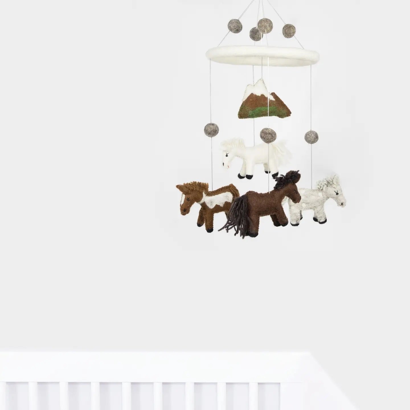 Children's mobile with horse figures and mountains on a white background