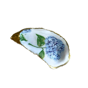 A small decorative dish or spoon-shaped piece with a white interior, blue floral pattern, green leaves, and a gold-toned rim, shown on a plain white background.