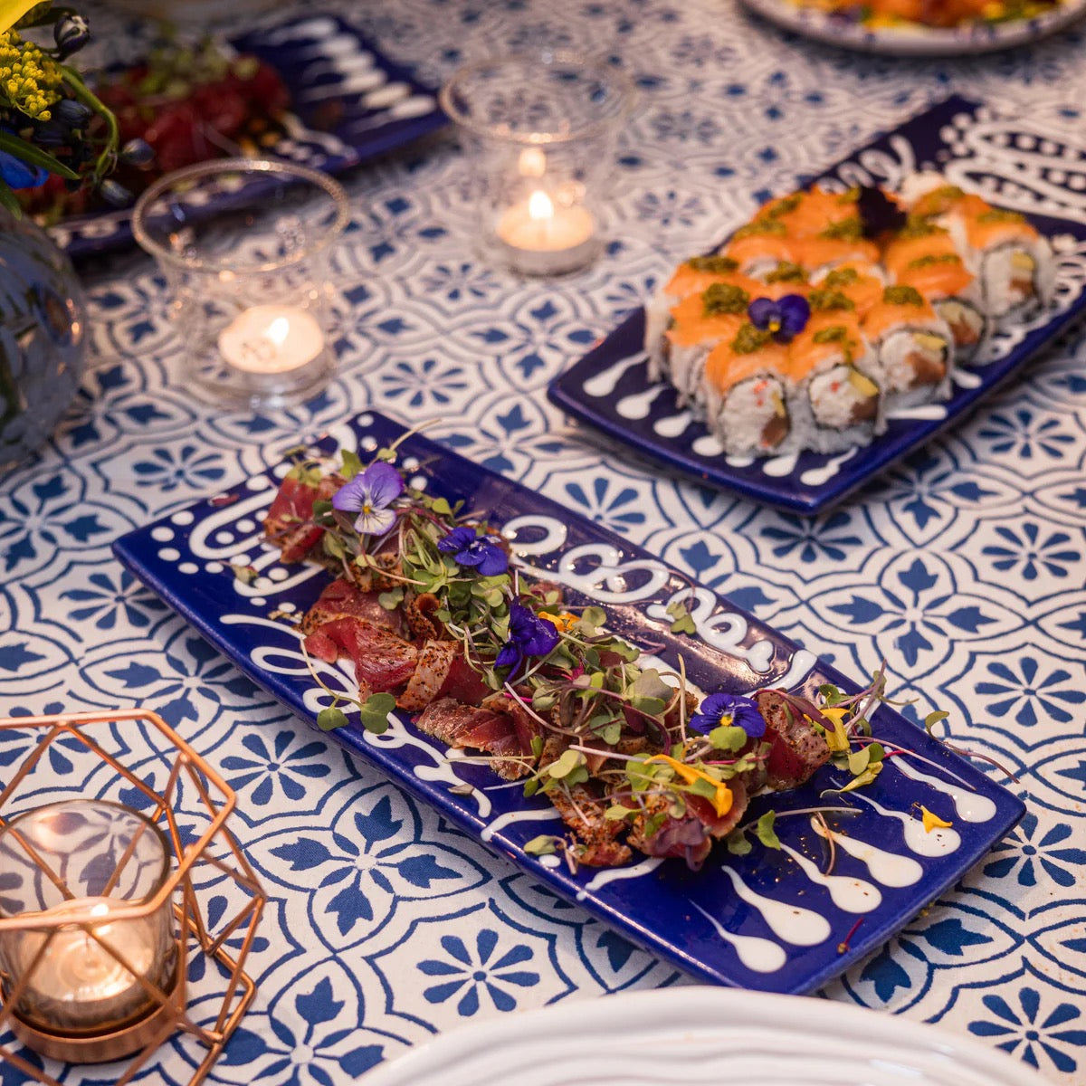 Plated dishes of food on a table with decorative plates and candles