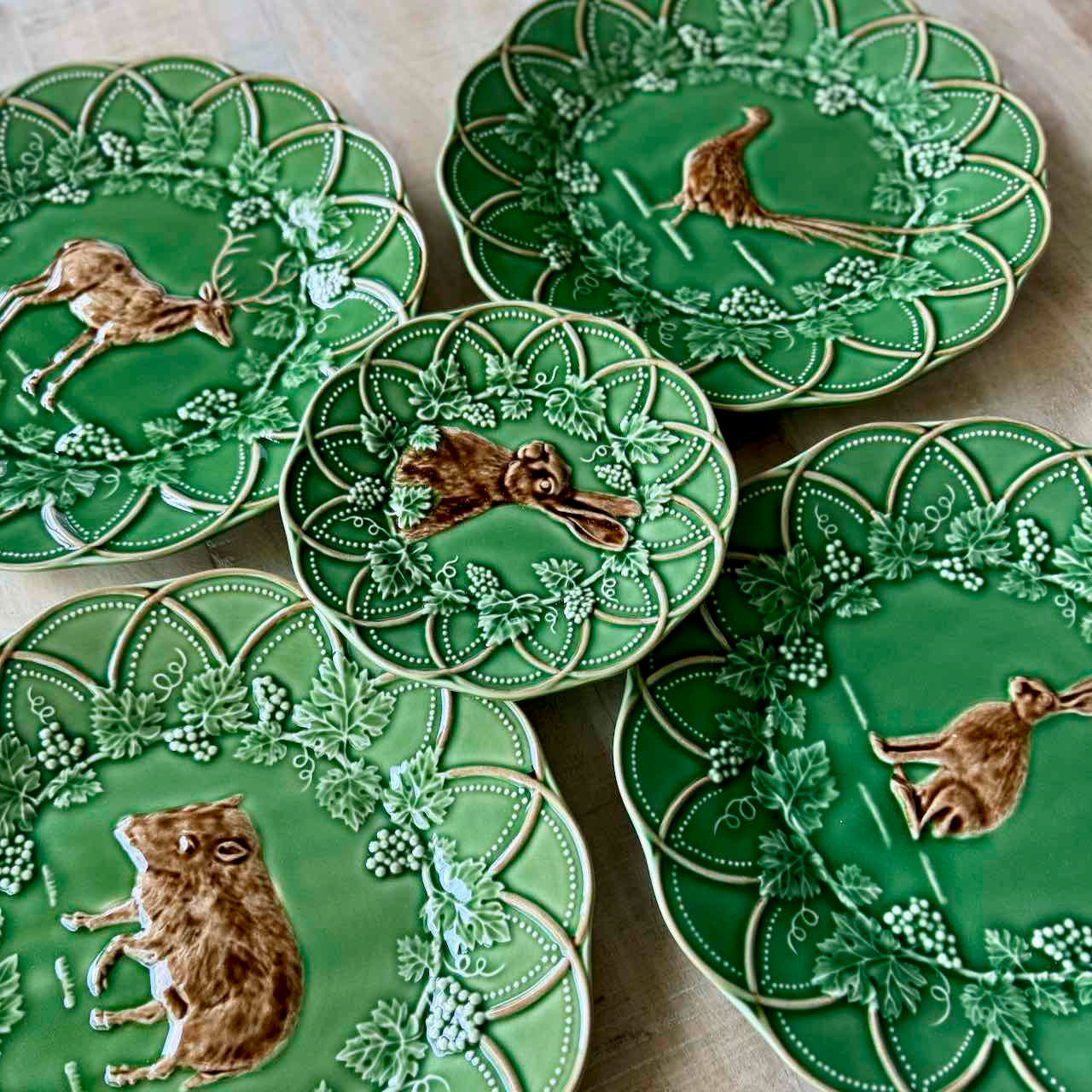 Set of green ceramic plates with animal illustrations on a wooden surface