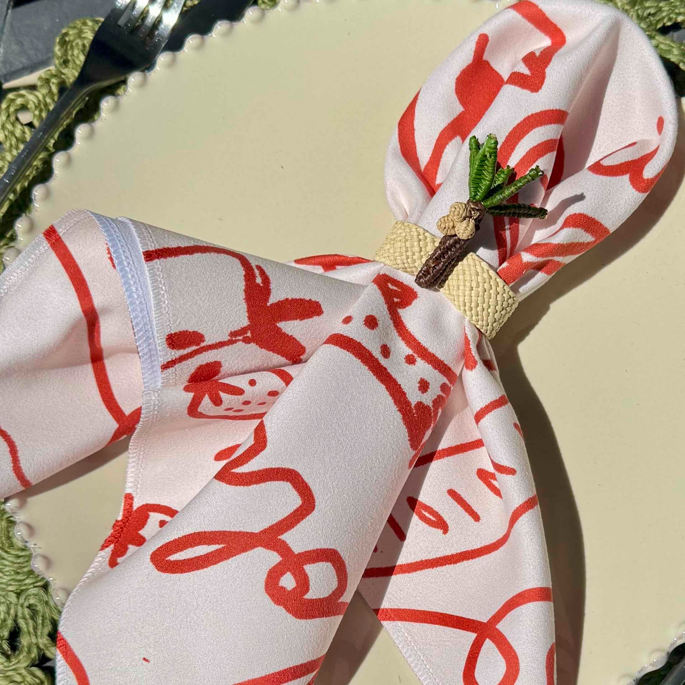 Napkin with red patterns and a decorative pin on a beige surface