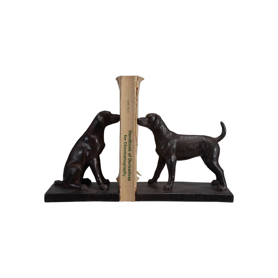Bronze bookends shaped like dogs holding a ruler on a white background