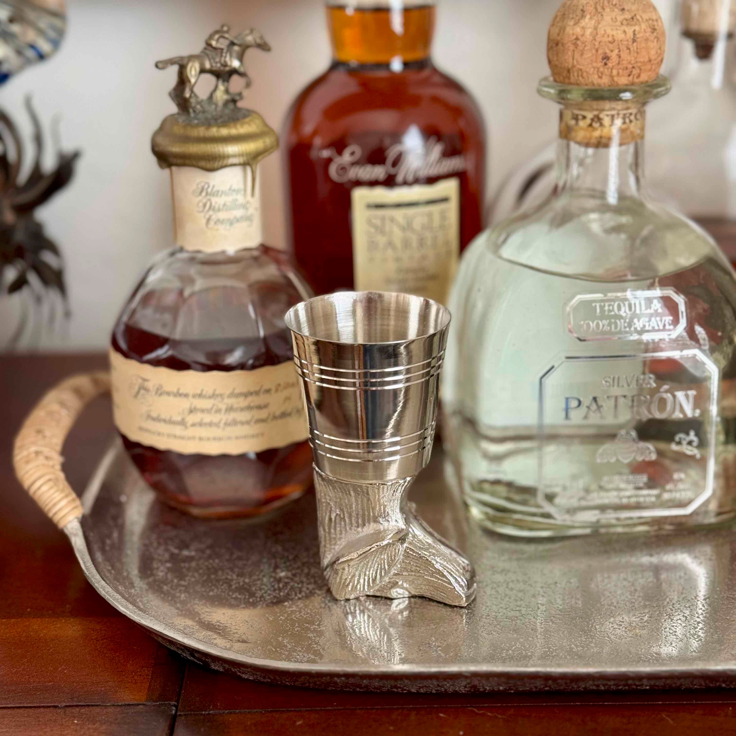 Bottles of liquor including a silver jigger on a tray