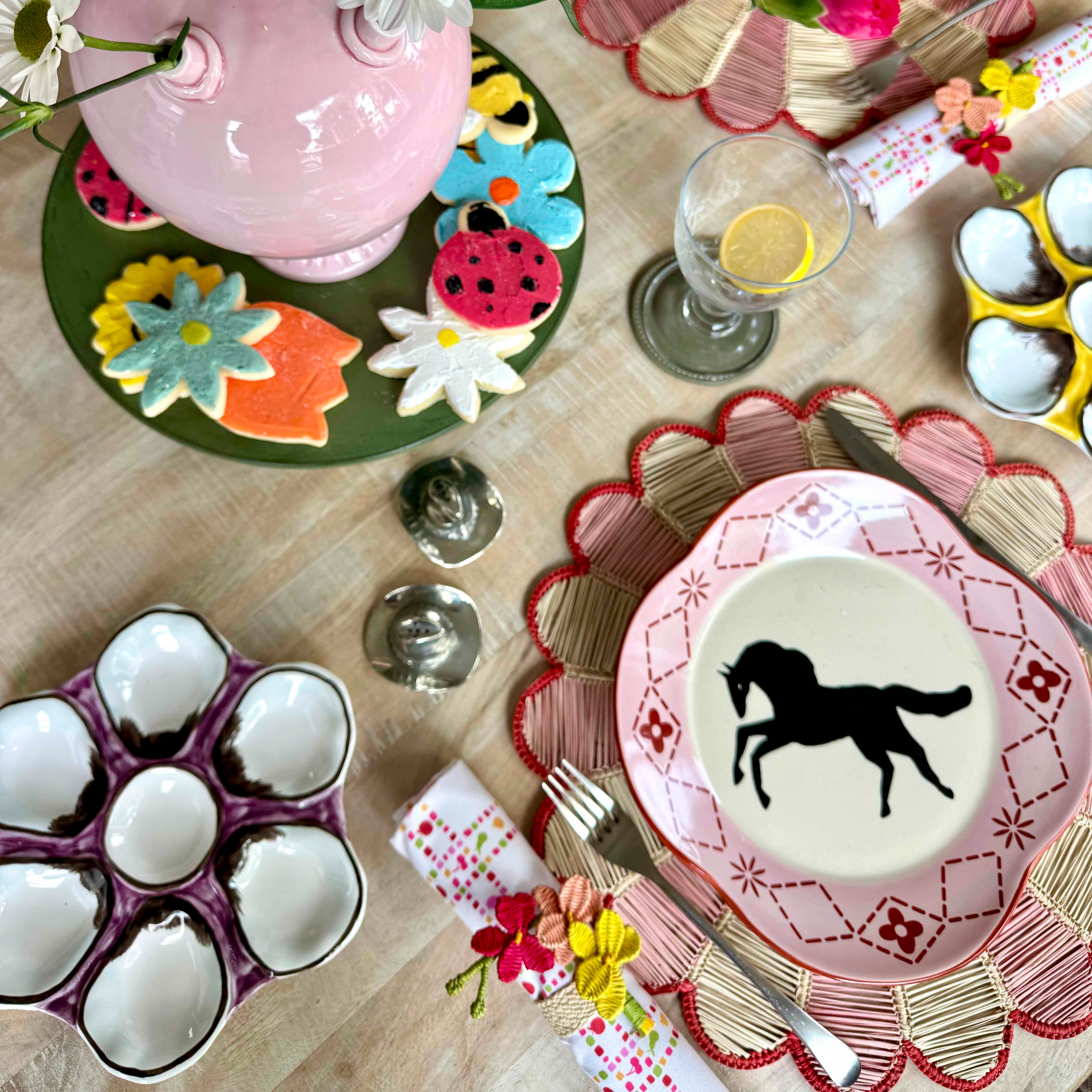 Dining table setting with decorative plates, glasses, and cutlery on a wooden surface.