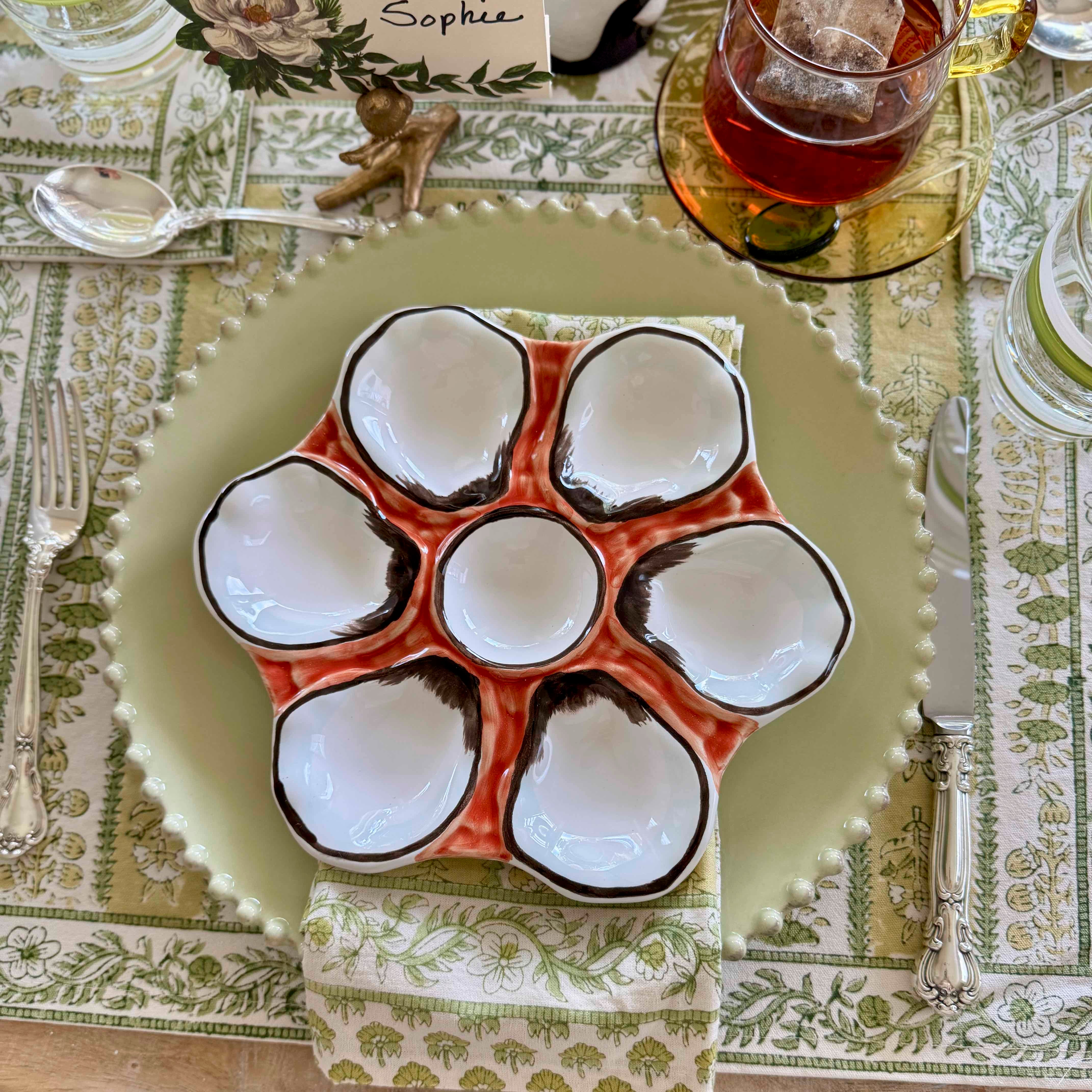 Ceramic oyster plate with six individual compartments on a decorative table setting.