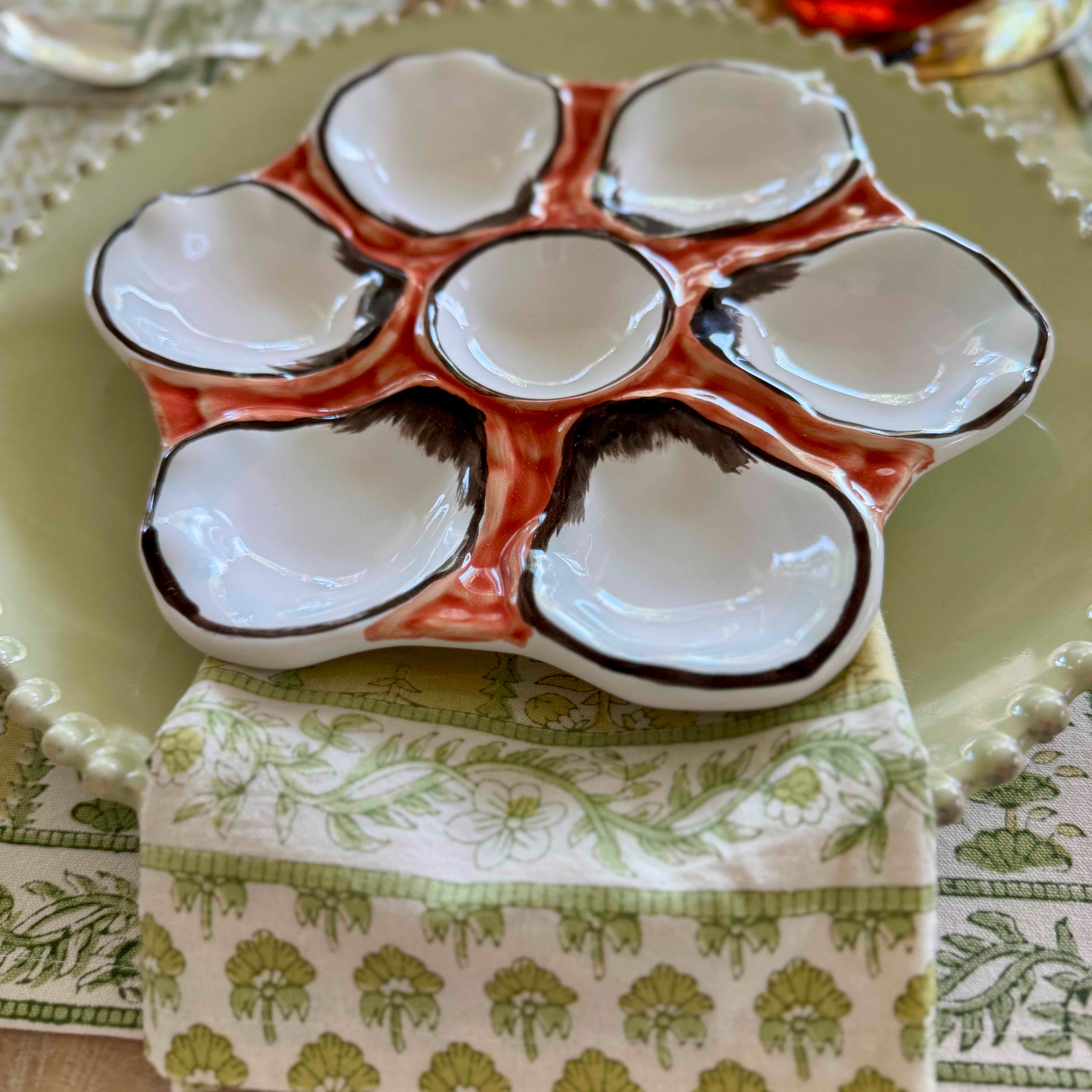 Ceramic oyster plate with multiple compartments on a patterned tablecloth