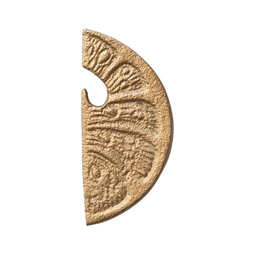 Bronze-colored half-circle object with engraved patterns on a white background