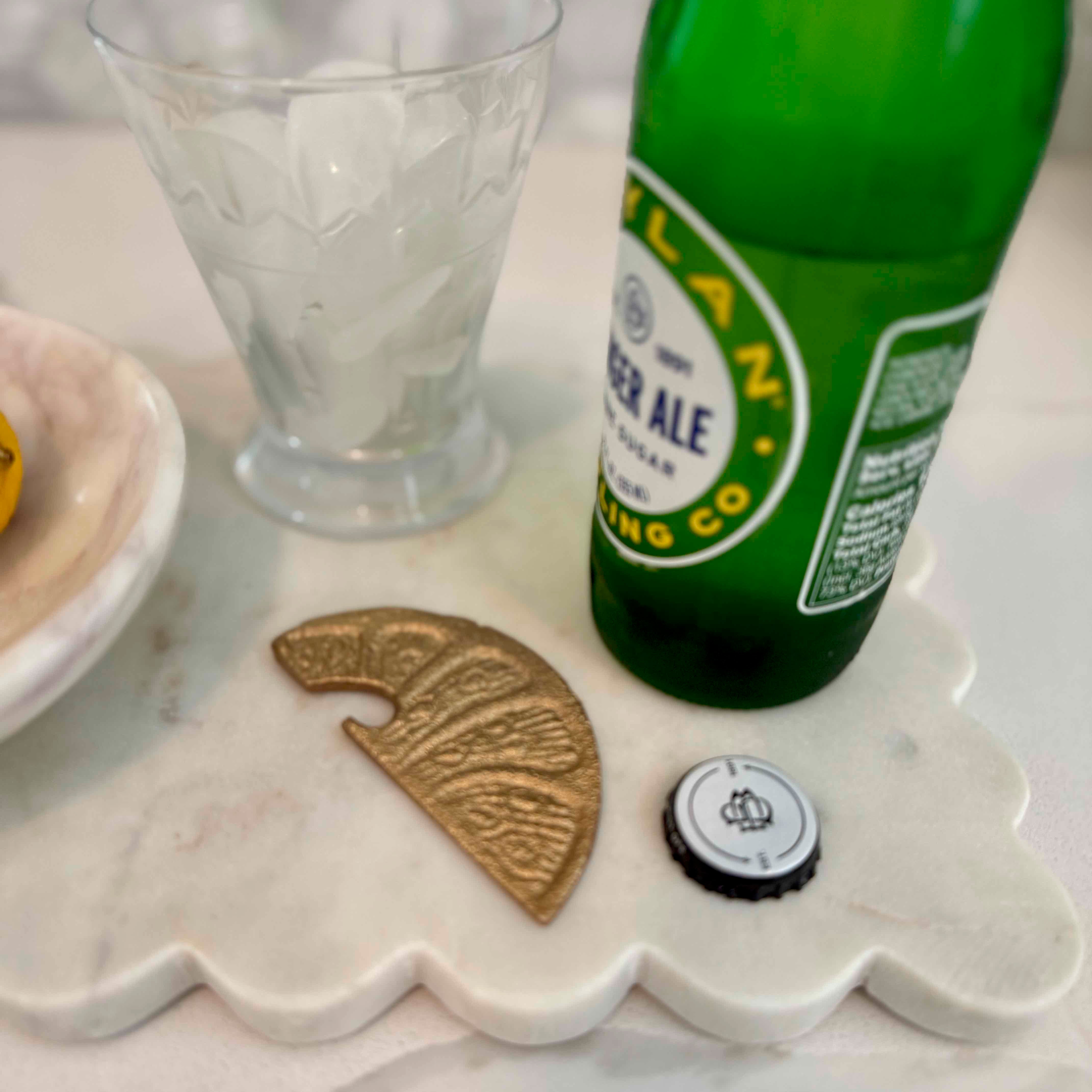 Green bottle of Peroni beer with a glass, coin, and bottle cap on a marble surface.