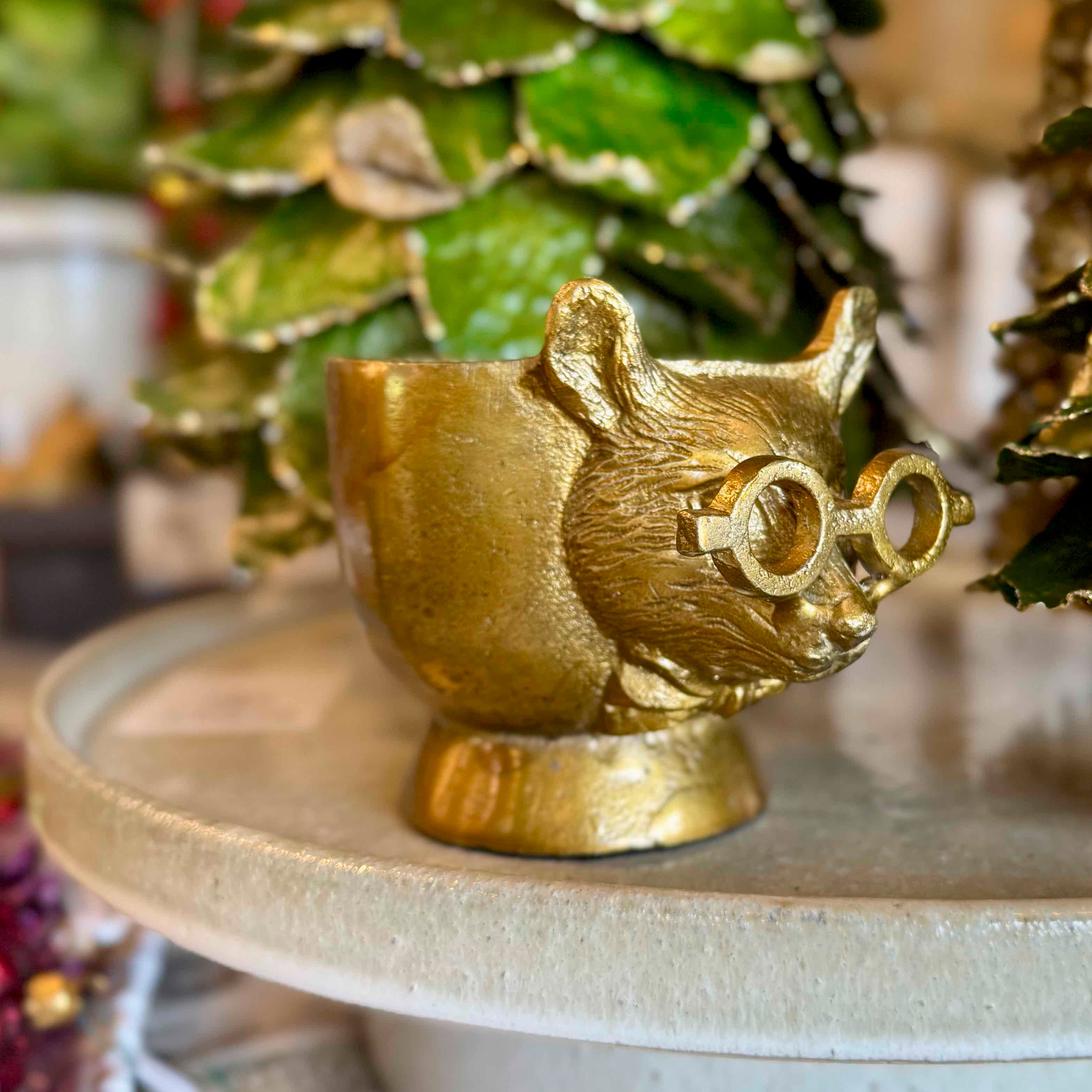 Gold cat-shaped teapot on a surface with a blurred background