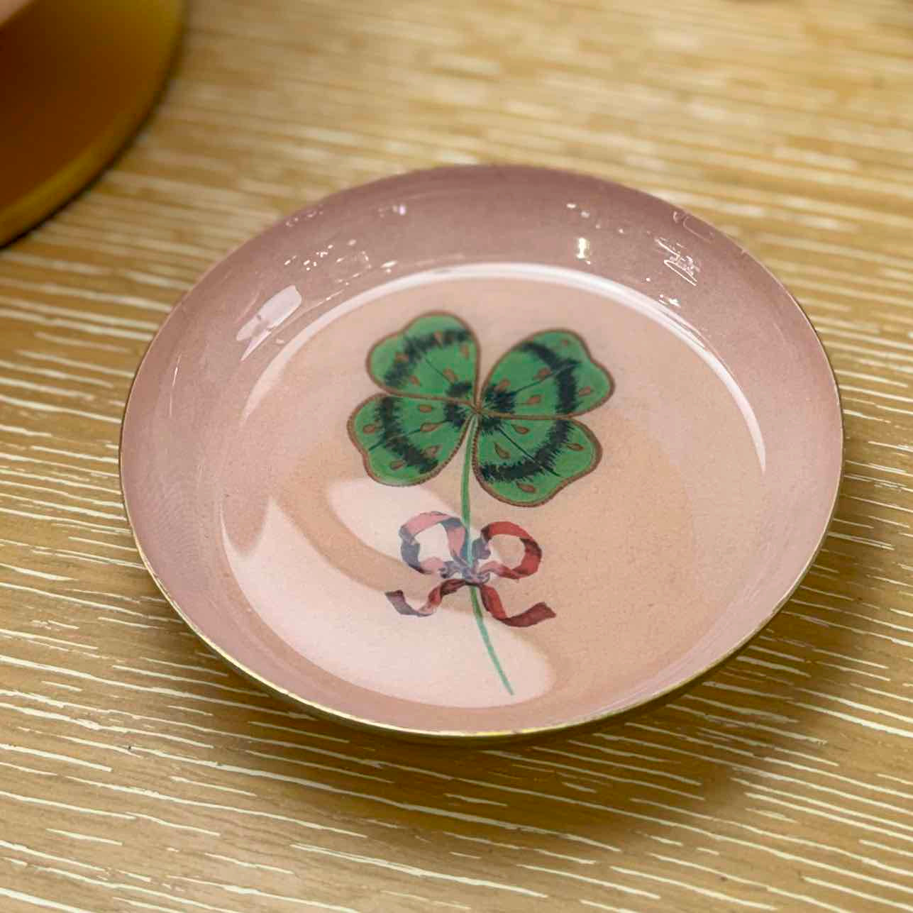 Round ceramic plate with a four-leaf clover design on a textured surface