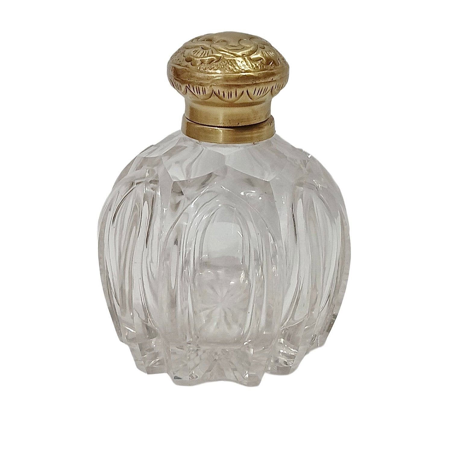 Clear glass perfume bottle with a gold cap on a white background