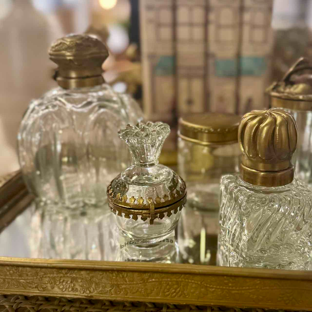 Vintage-style glass perfume bottles with gold caps on a reflective surface.